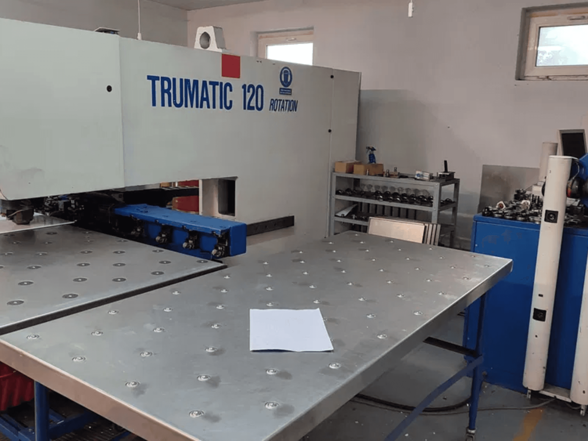 TRUMPF TRUMATIC 120R CNC punching machine viewed from the front, featuring a metallic table with punched holes and a blank sheet.