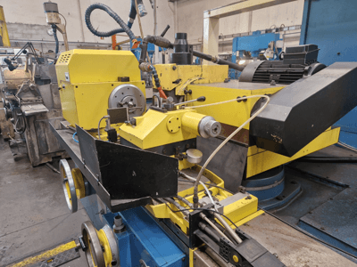 Yellow industrial machine with a black section, featuring a dial and hoses, viewed from the front at a slight angle.