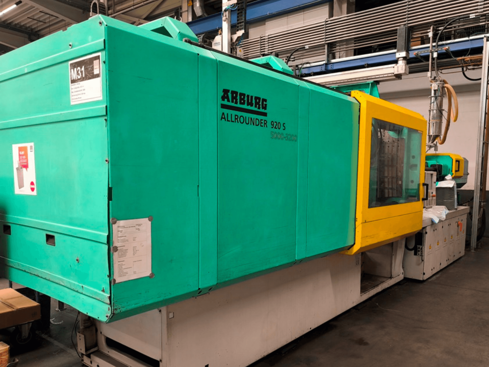 Arburg Allrounder 920 S injection molding machine in aqua blue and yellow, side view showing control panel and components.