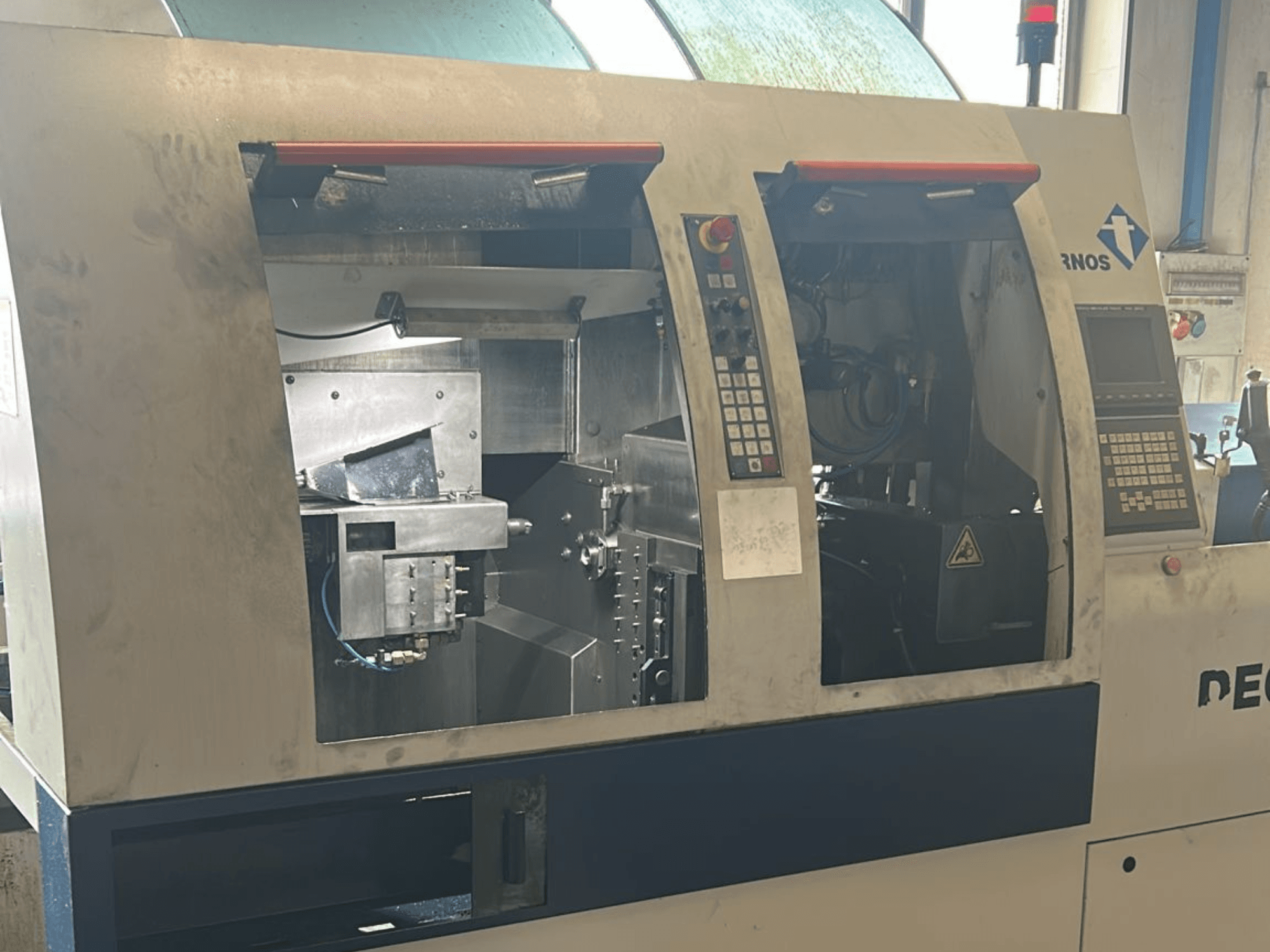 Alt text: Front view of TORNOS Deco 13 b Swiss Type Turning Machine with control panels and internal components visible.