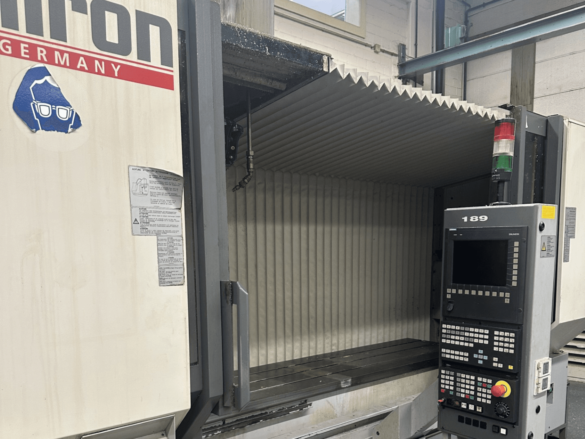 Alt text: Front view of a Hermle CNC machine with a control panel showing buttons and a display, featuring an open work area.