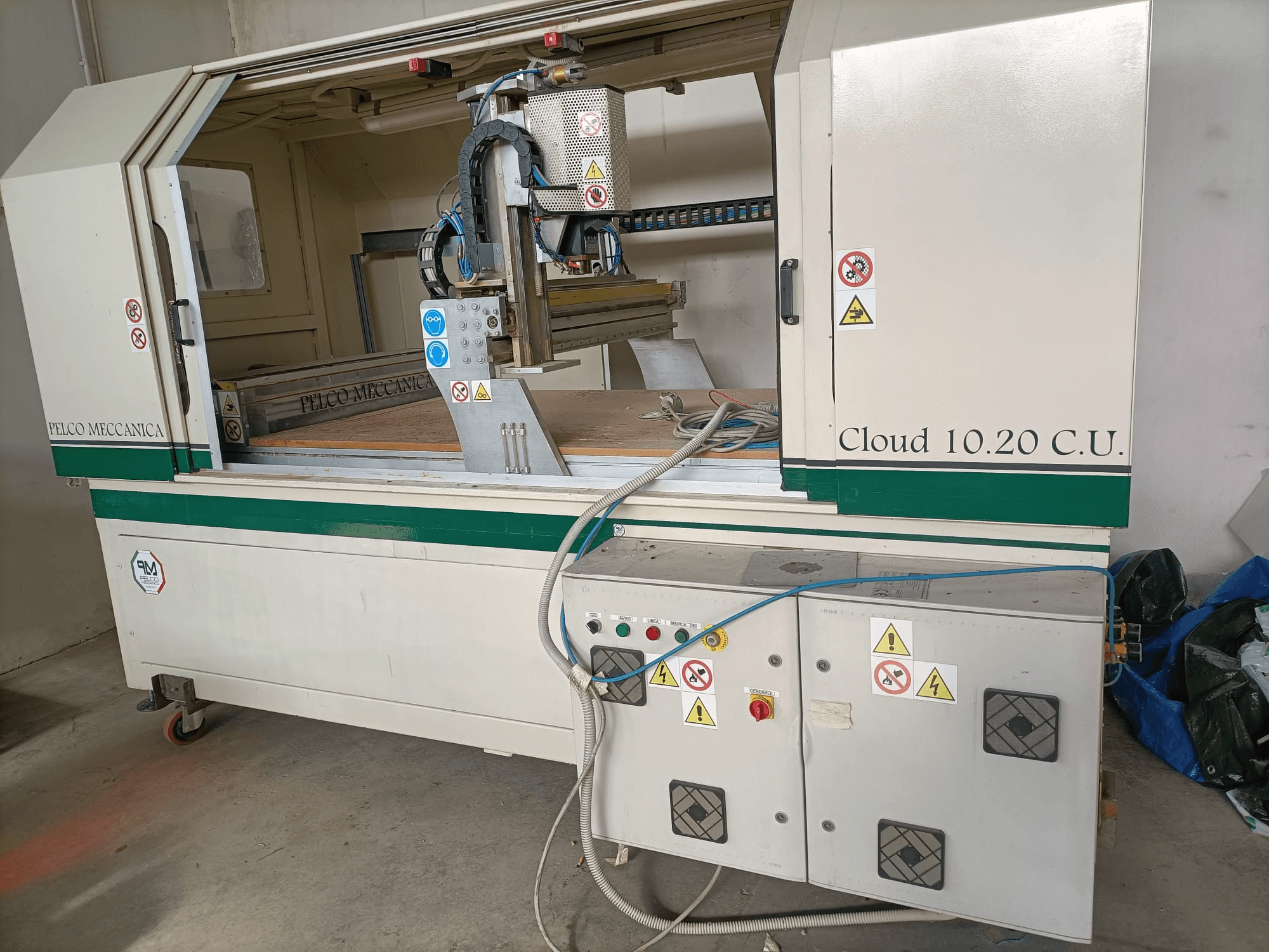 CNC router MECCANICA CLOUD 10.20 C.U., front view showing control panel and workspace, with safety labels and hoses visible.
