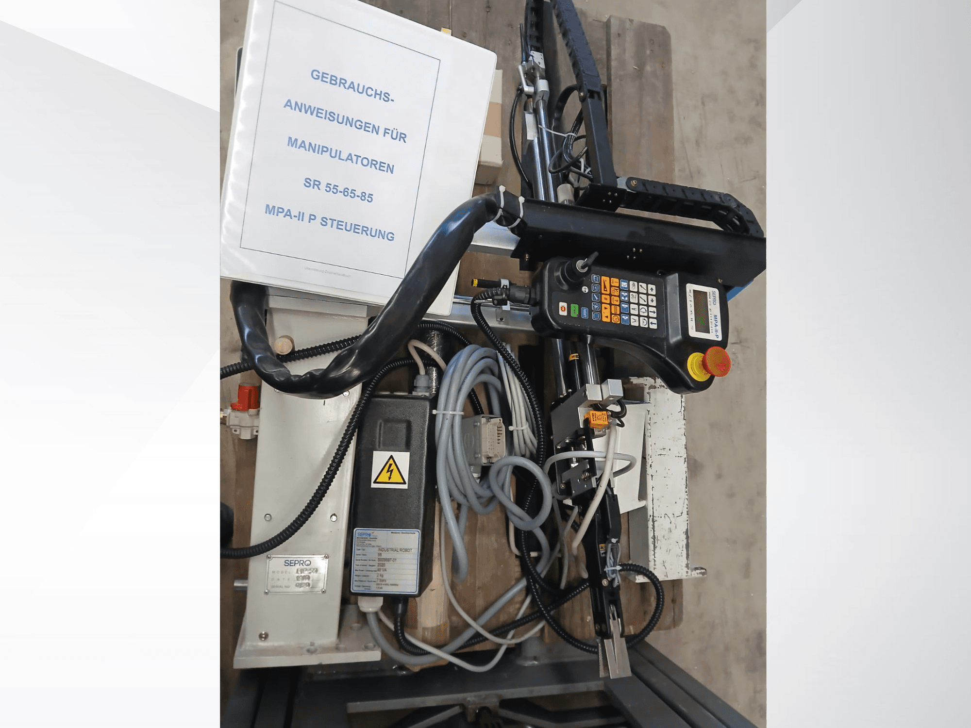 Sepro PIP-55 Gantry Robot control panel and components, viewed from the side, with user manual visible.