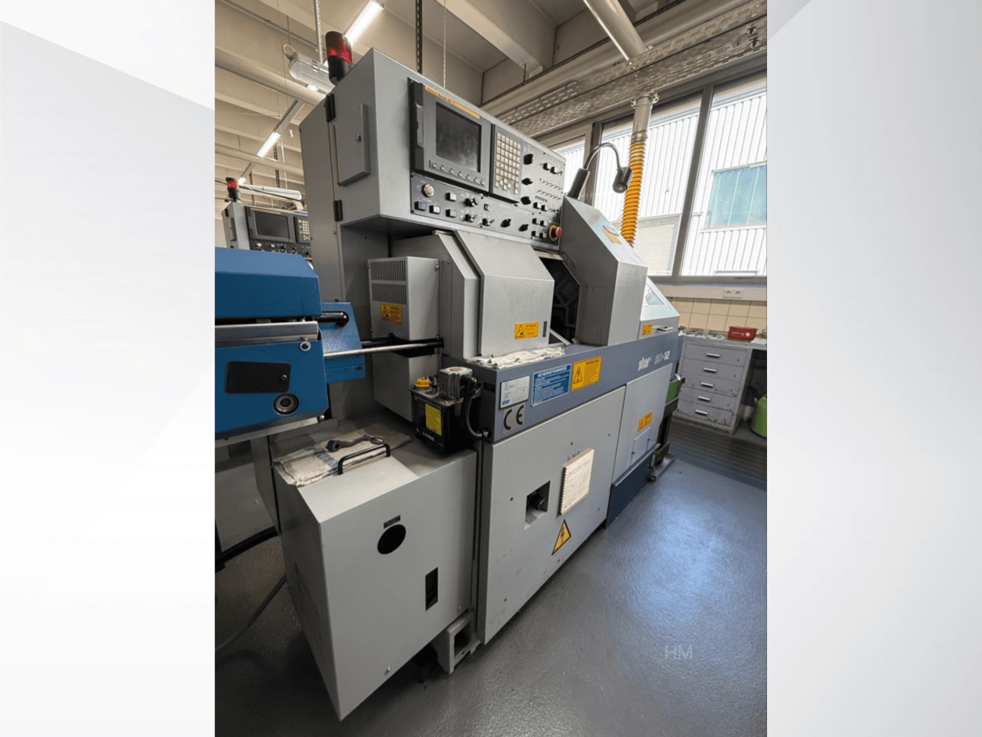 Front view of the lithec 3231 machine, showing control panel, motor, and blue feeding section in a well-lit industrial setting.