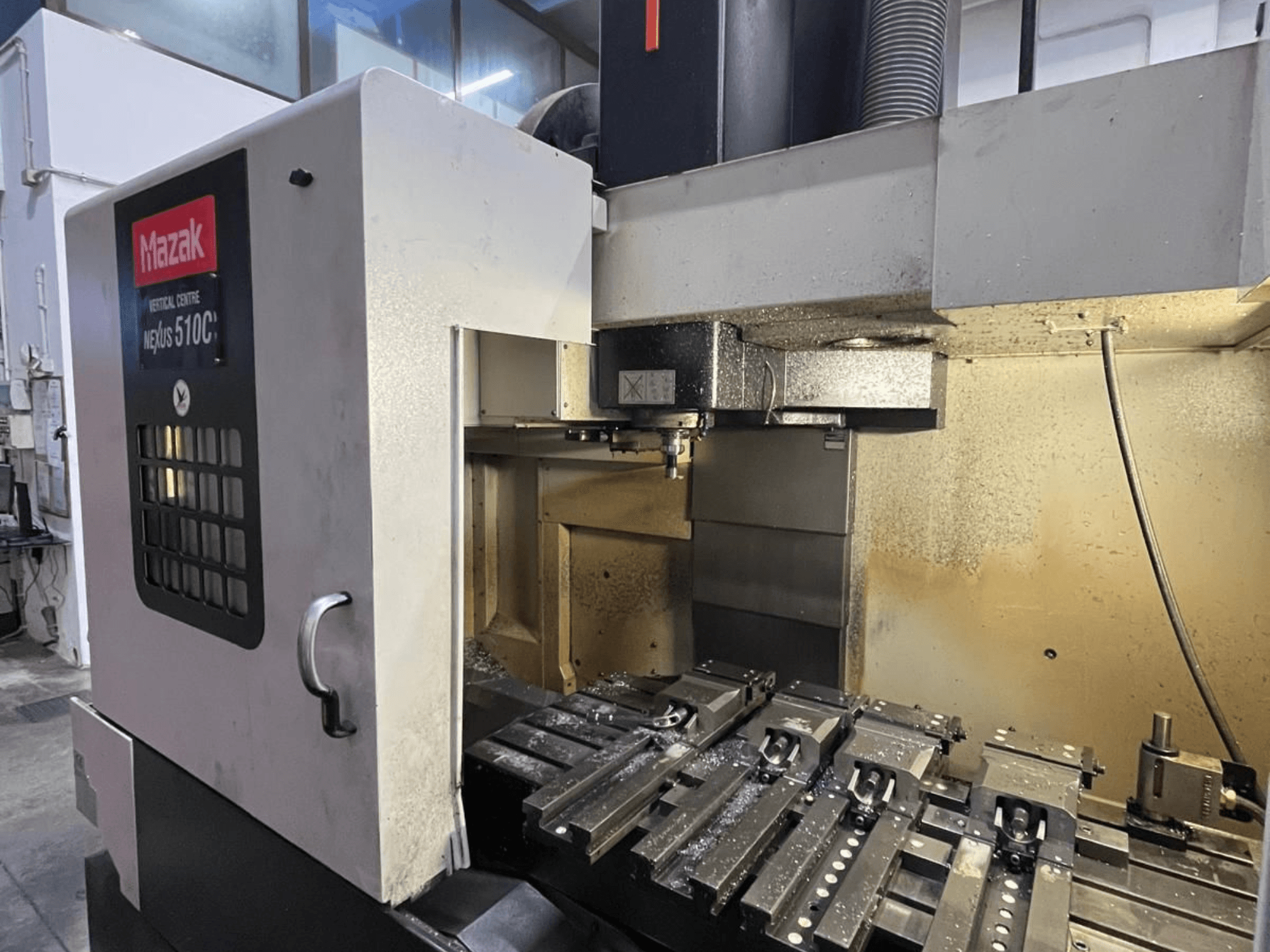Mazak VCN-510C NEXUS vertical machining centre, front view, showing milling table and tool holder in a workshop setting.