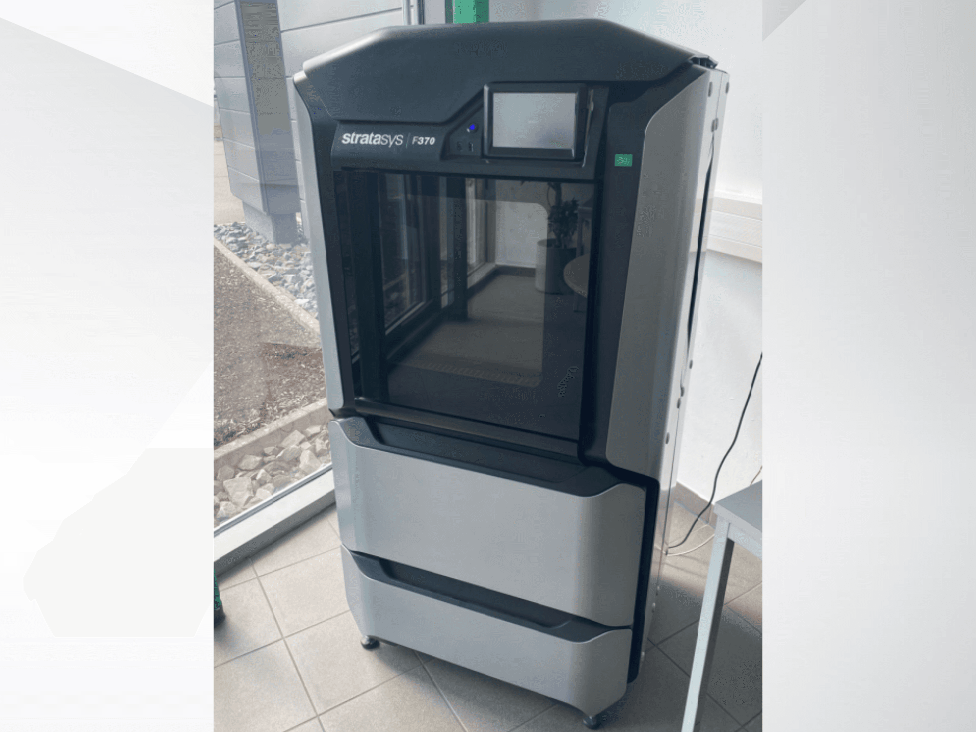 Stratasys F370 plastic 3D printer, front view, showcasing a sleek black and gray design with a touchscreen display.