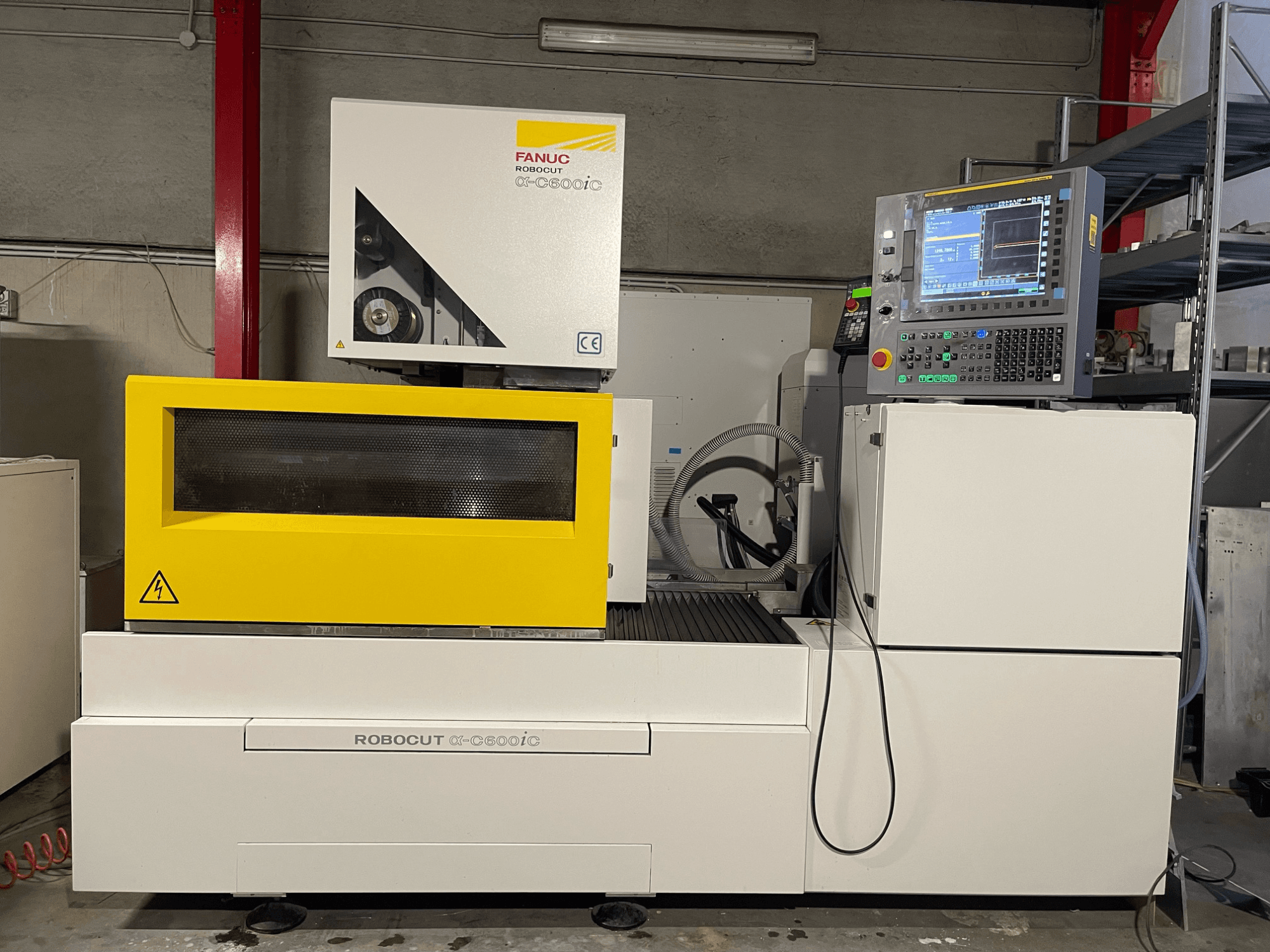 FANUC Robocut α-C600iC, side view of CNC machine with yellow safety cover and control panel, showcasing precision cutting capability.