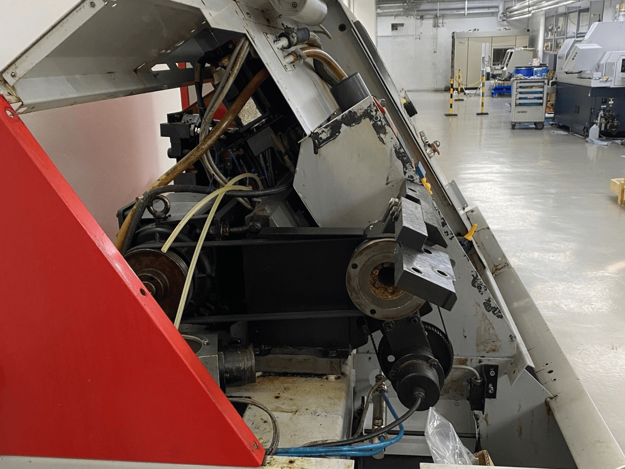 EMCO Emcoturn 325 horizontal turning machine, side view showing drive components and hydraulics in industrial setting.