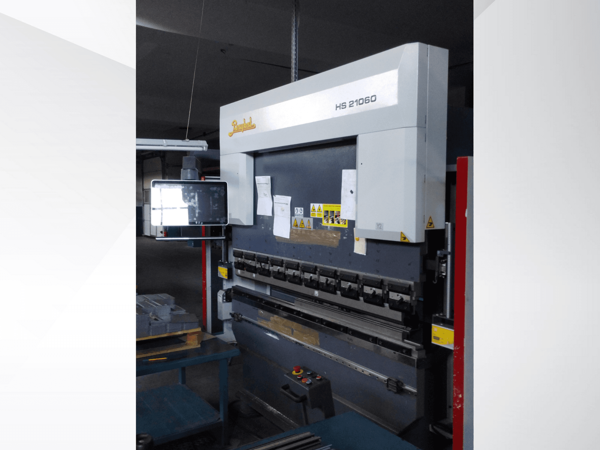 Beyeler HS 21060 press brake, front view, showing controls, a display screen, and warning labels in a workshop setting.