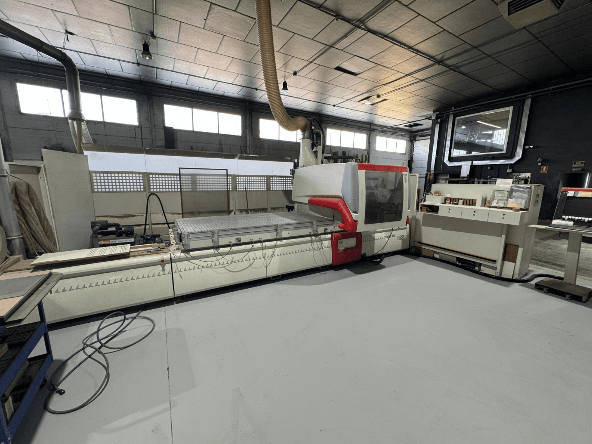 CNC machine in a workshop, front view with red accents, equipped with control panel and work surface, for precision cutting.