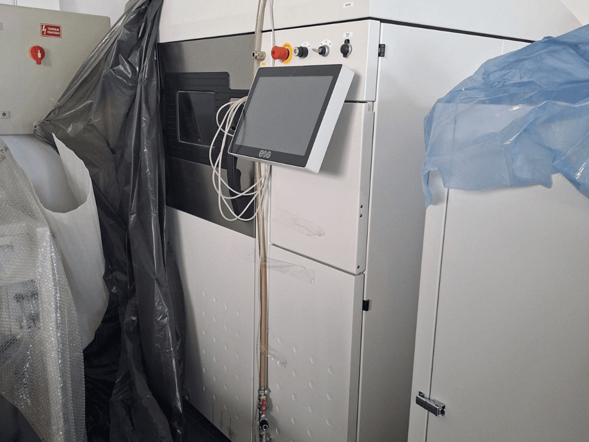 EOS M 290 metal 3D printer front view, featuring a touchscreen, control panel, and protective coverings.