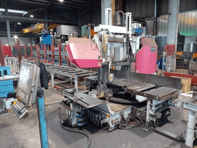 Behringer band saw machine in a factory, front view, featuring a large cutting blade and control panel with buttons.