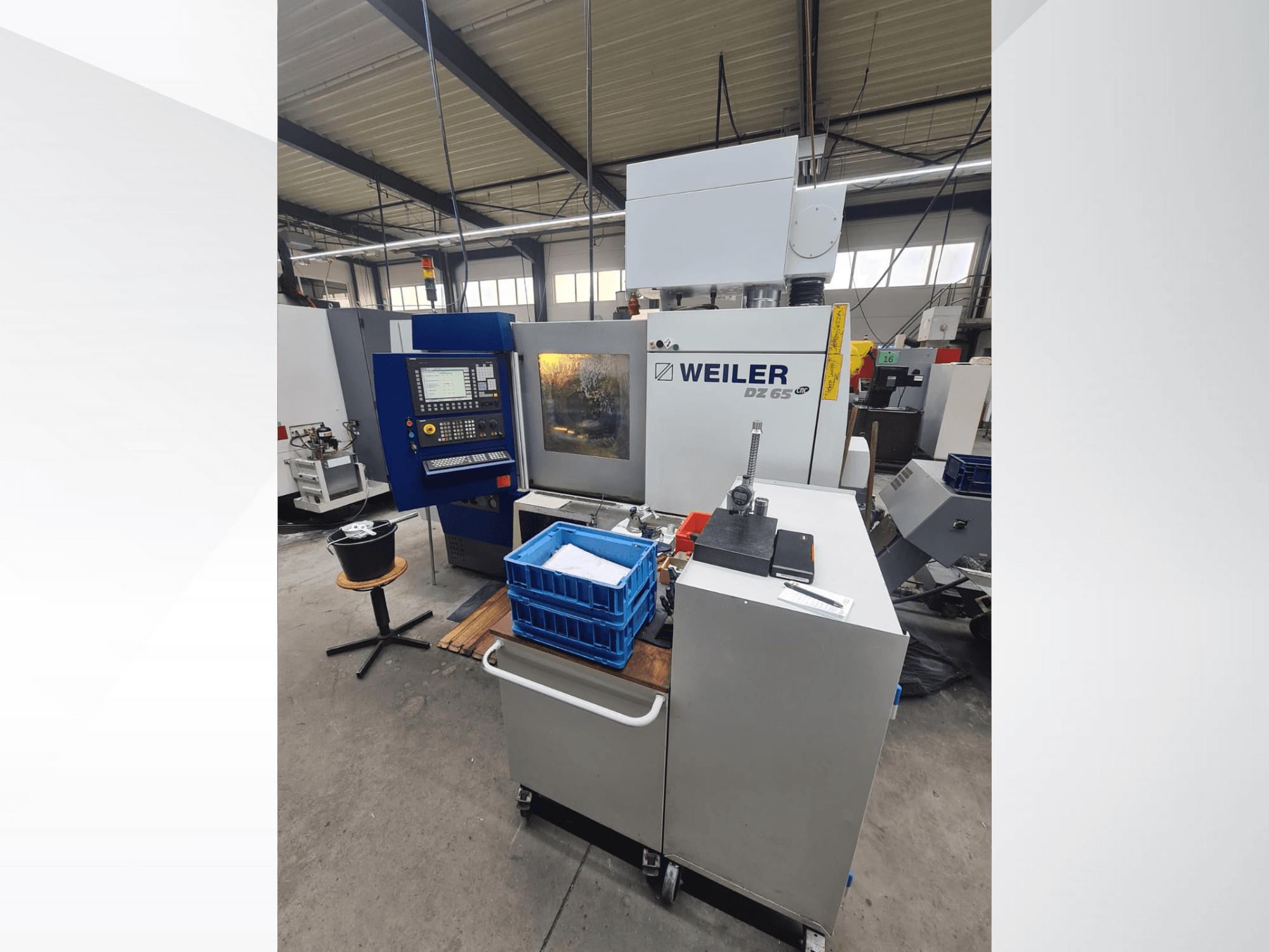 Weiler DZ 65 CNC machine in a workshop, front view with control panel, tools, and blue storage bins visible.