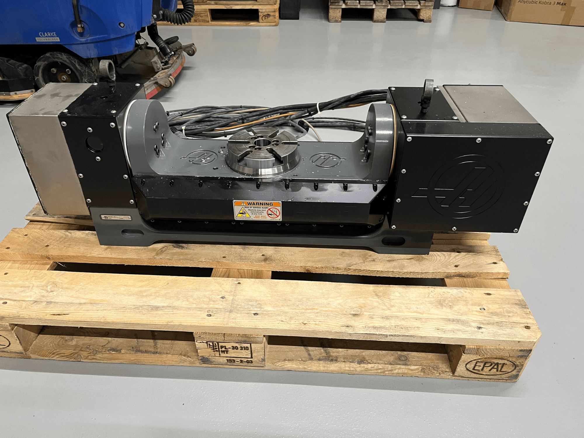 Z-axis motor drive unit on wooden pallet, showing front view. Features metallic casing and warning labels.