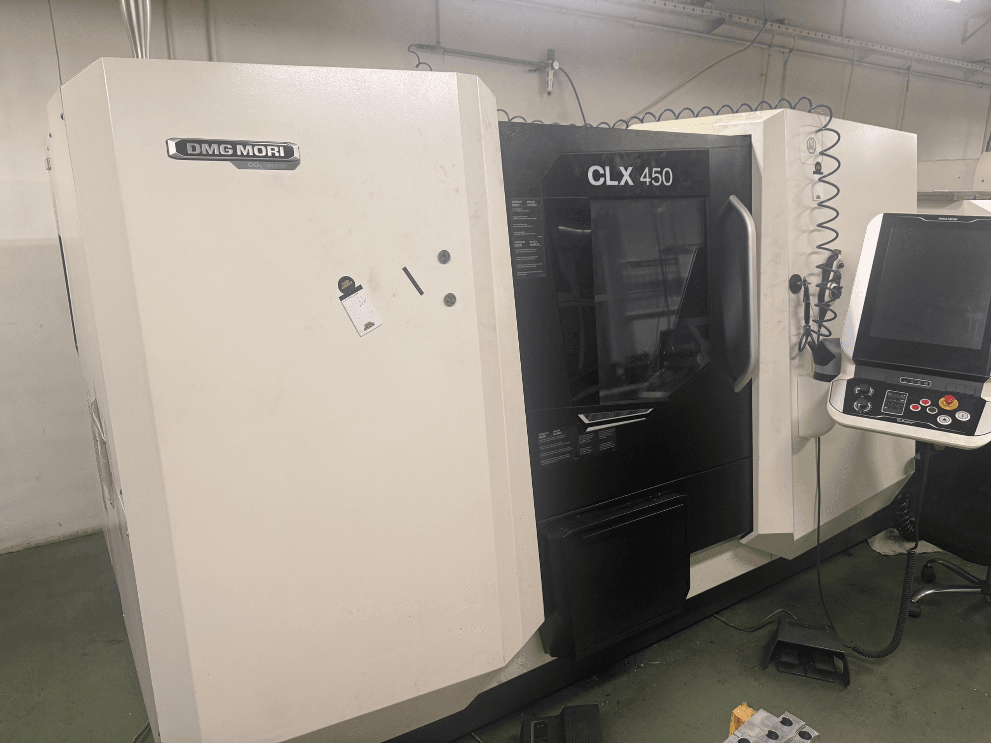 DMG MORI CLX 450 CNC machine, side view with control panel, visible operational buttons, and clean workspace.