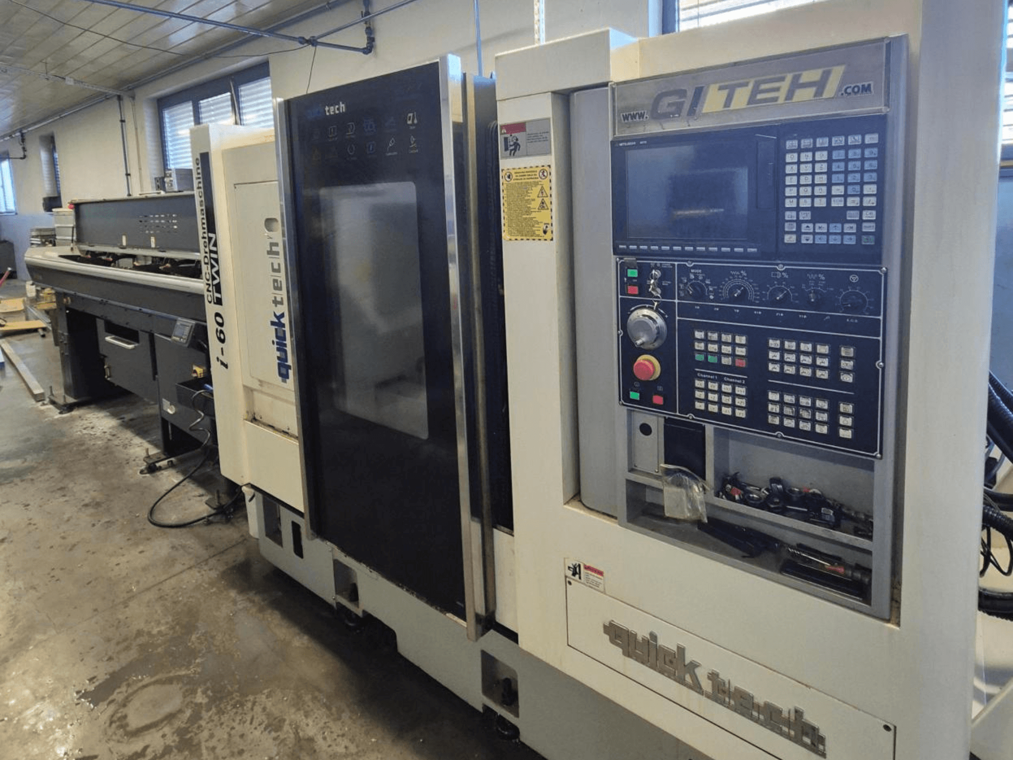 Quick Tech i-60 twin CNC machine, front view, featuring GITEH control panel and operational buttons, in a workshop setting.
