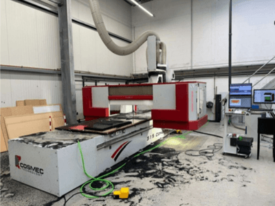 Cosmec 515 CNC machine in workshop with a computer terminal, showing a front view and dust scattered on the surface.