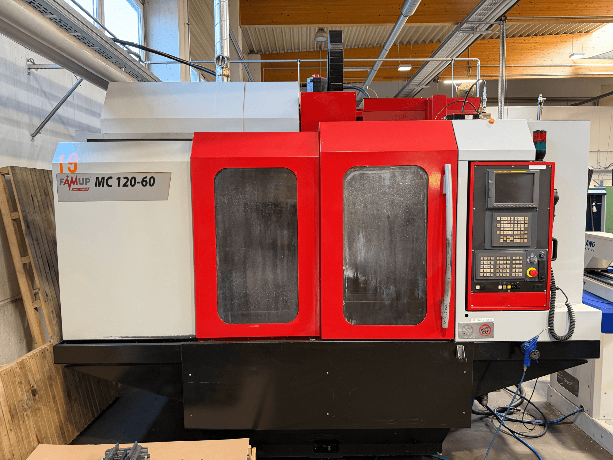 Front view of EMCO MC 120-60 vertical machining center featuring red and white casing, control panel, and display screen.