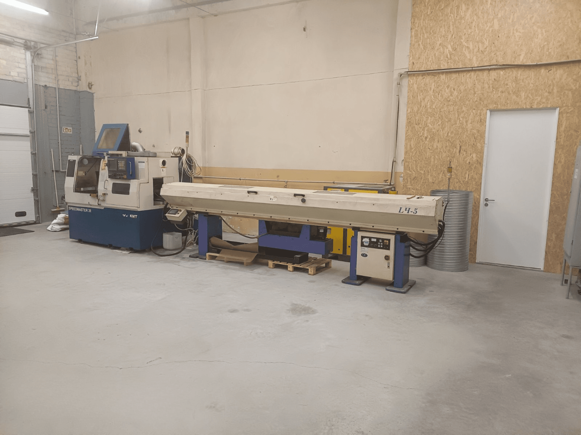 Industrial workshop featuring KMT Speedmaster 34 machine and L4.5, viewed from the front, with visible controls and machinery.