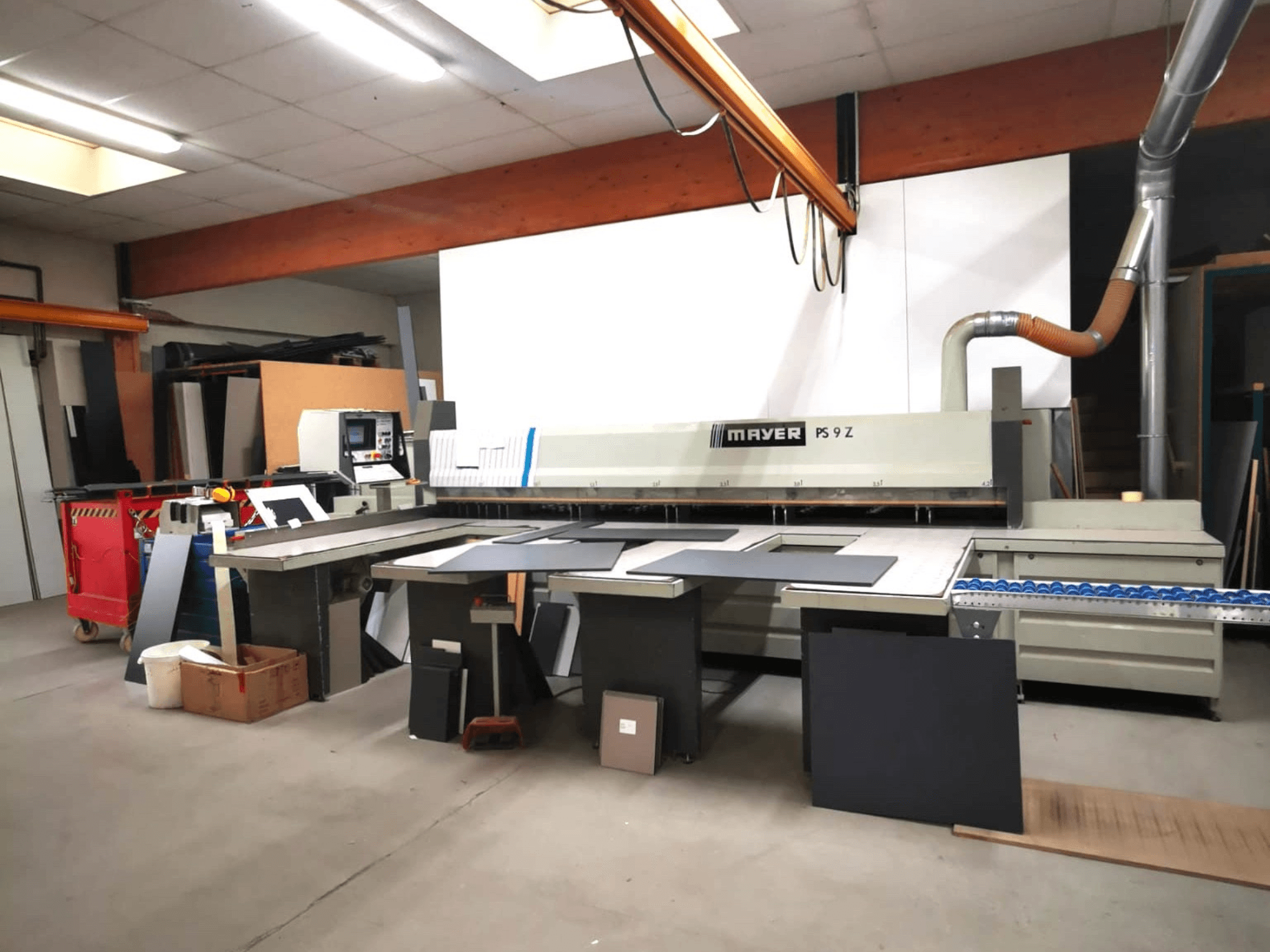 MAYER PS9 Z cutting machine in a workshop, front view, with various materials and a conveyor system visible.