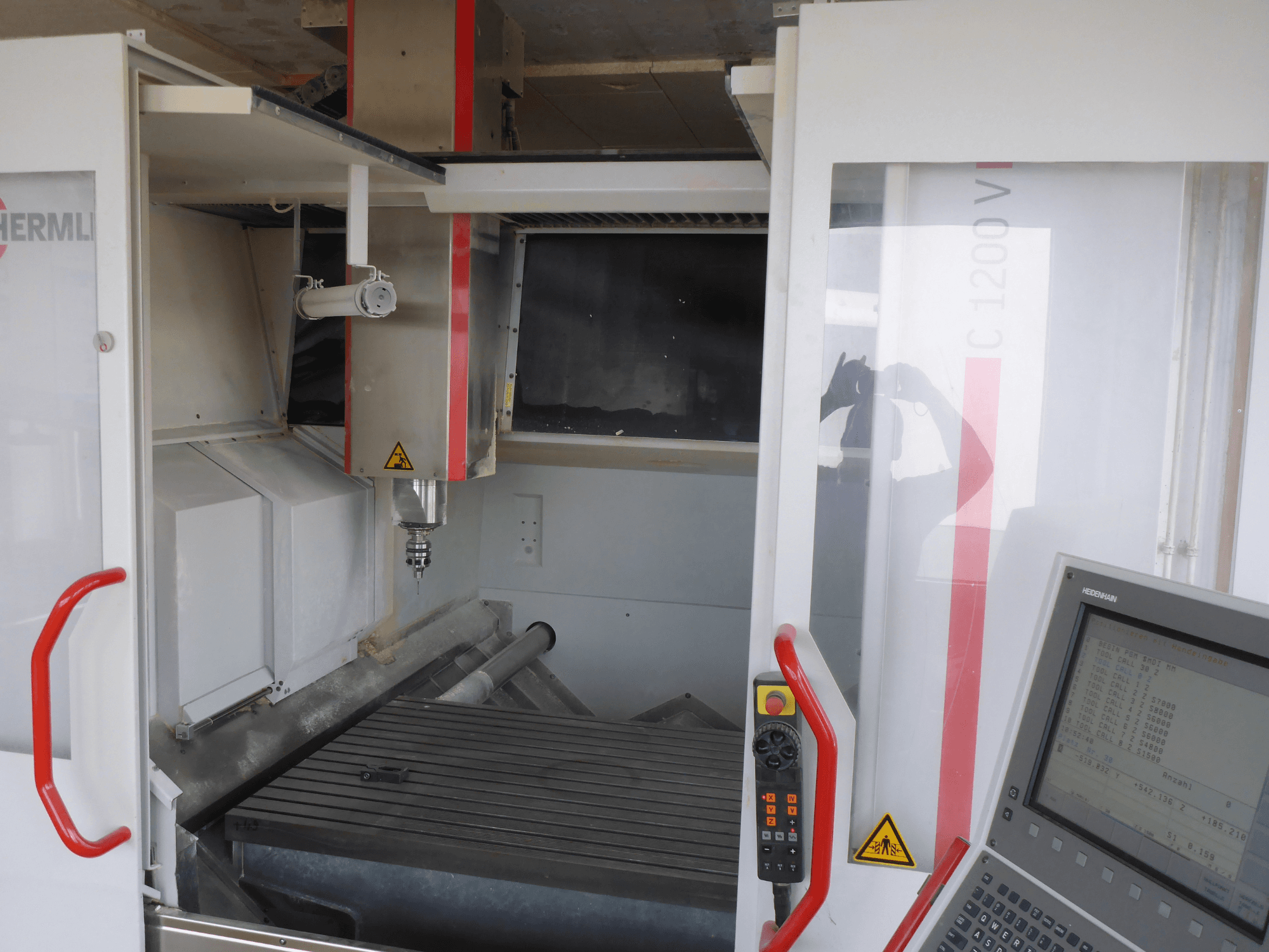 HERMLE C 1200 vertical machining centre interior showing tool holder, control panel, and worktable from a front view.