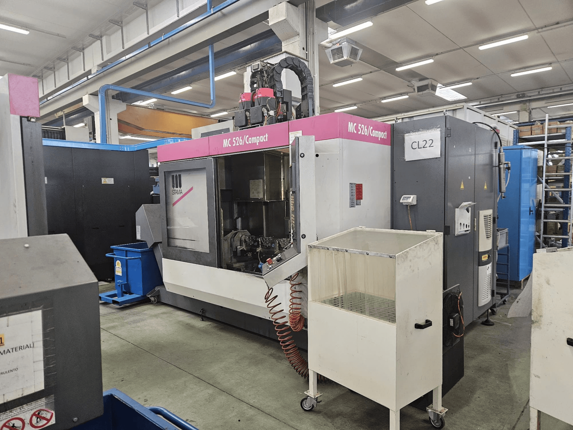 MC 526 Compact CNC machine from Stama, side view, showing control panel, coolant tank, and adjacent machinery.