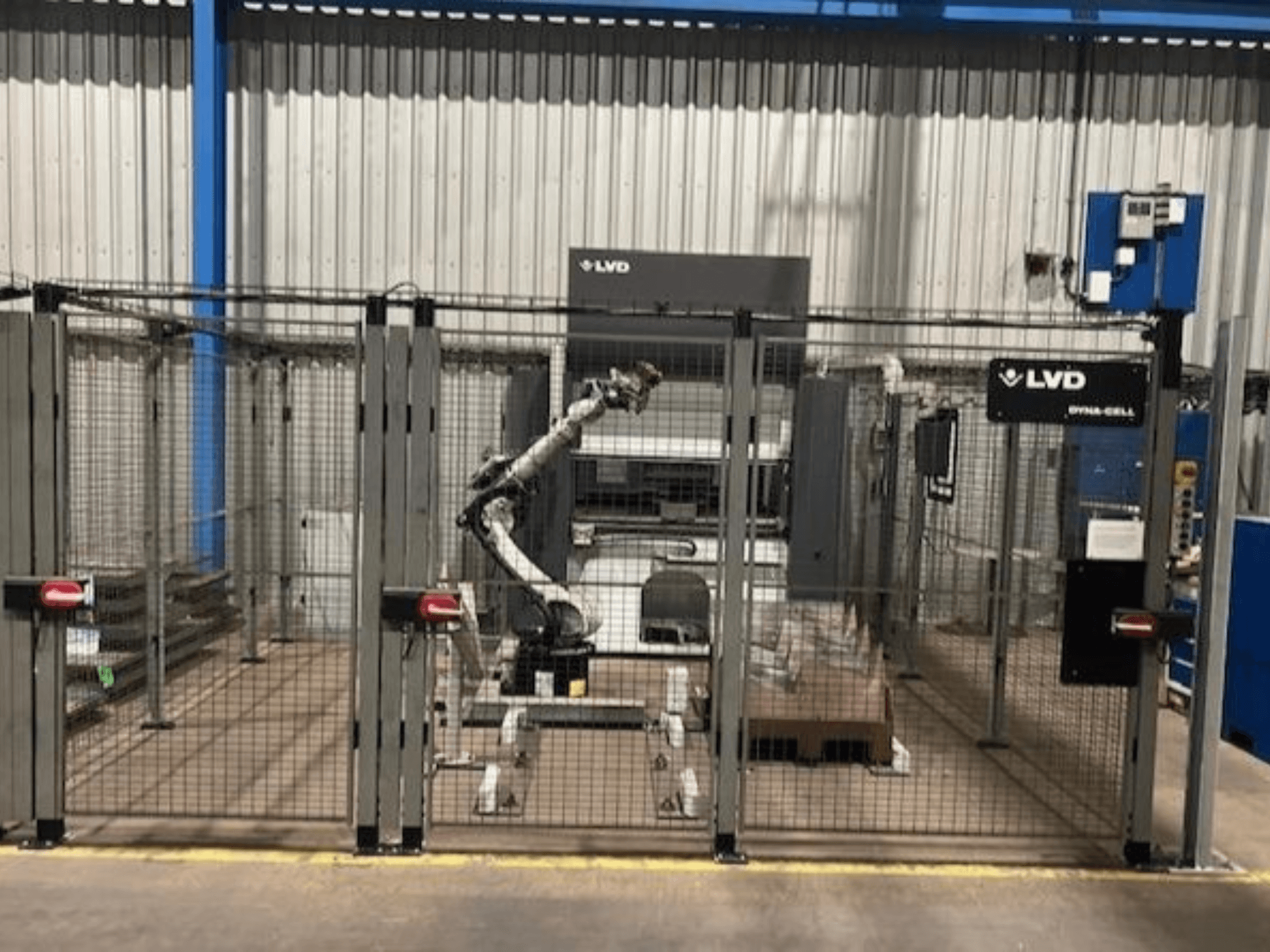 LVD Dyna-Cell robotic workstation in a fenced enclosure, front view, featuring robotic arm and control panel.