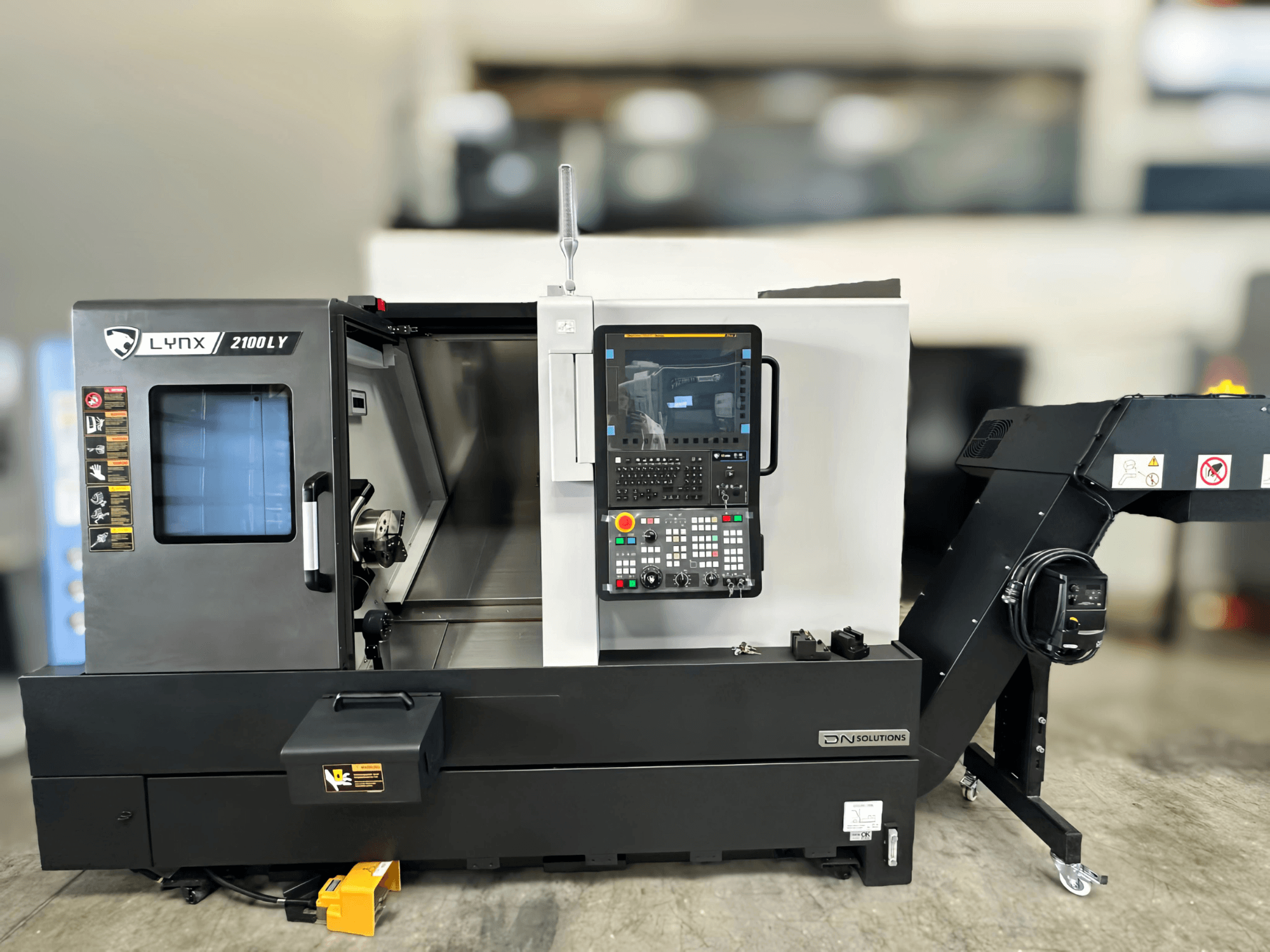 Horizontal turning machine DN SOLUTIONS LYNX 2100LYB, front view, featuring control panel and open door revealing the interior.