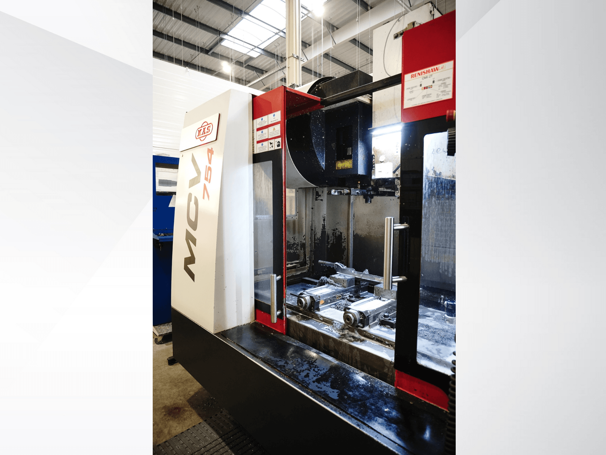 TAKUMI MCV 754 CNC milling machine, front view, showcasing metal shavings and precision tooling in a workshop setting.