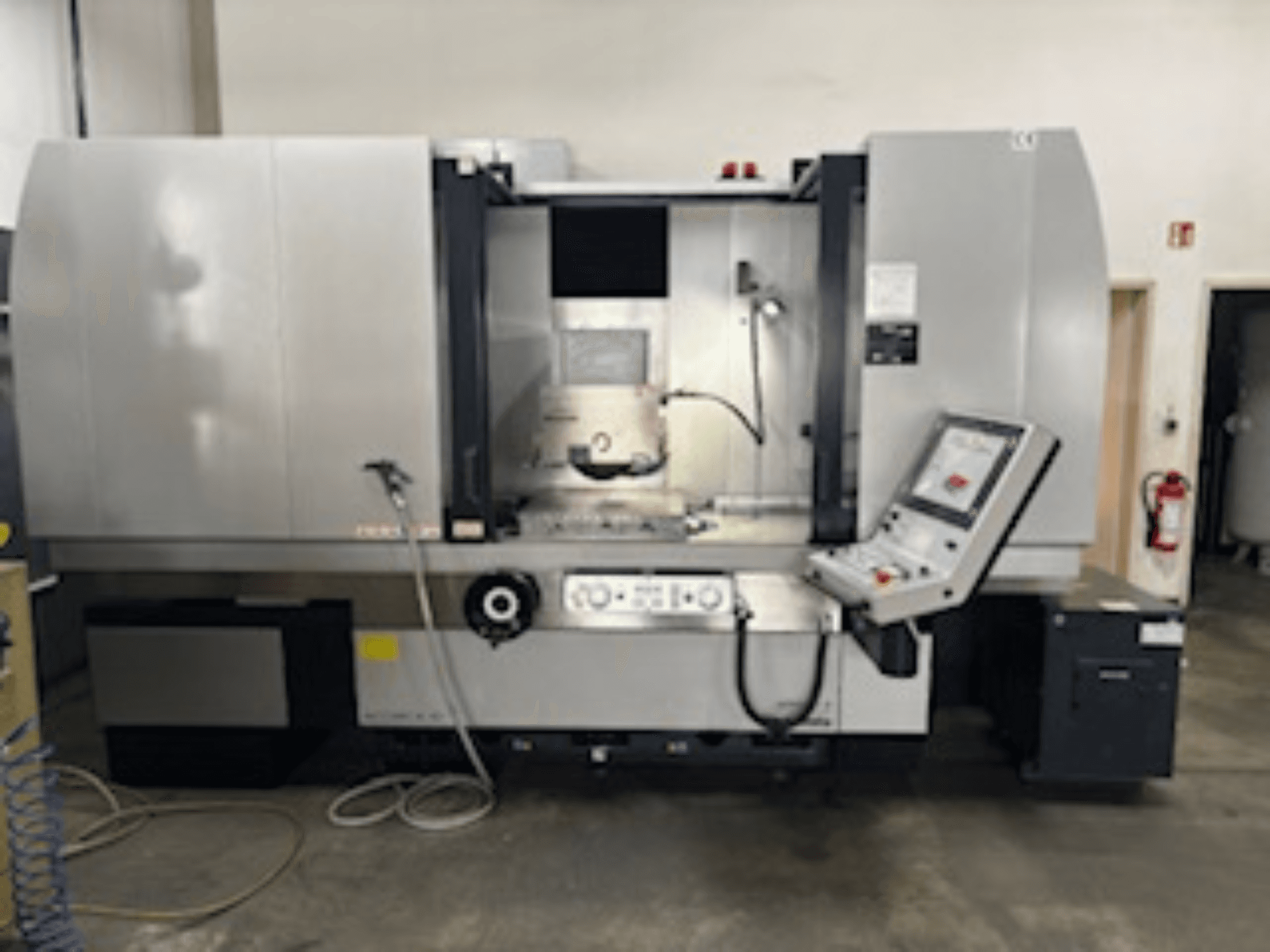 CNC milling machine front view with control panel, visible coolant system, and machining area; brand and model not specified.