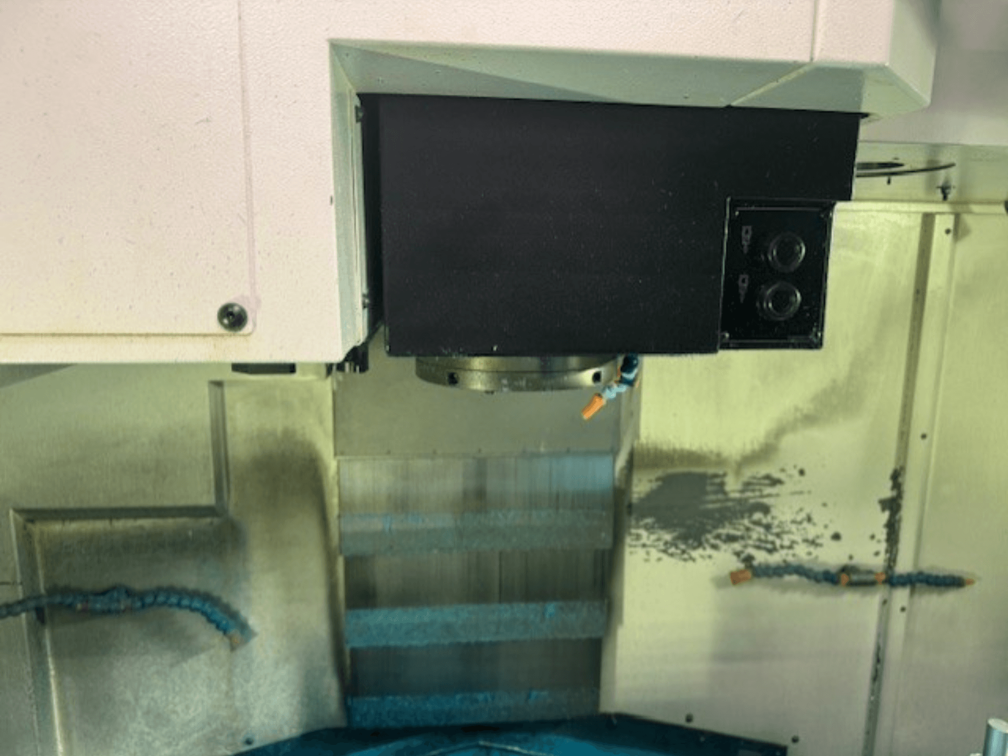 Close-up of a CNC milling machine control panel and tool holder, showcasing brand details, buttons, and work surface.