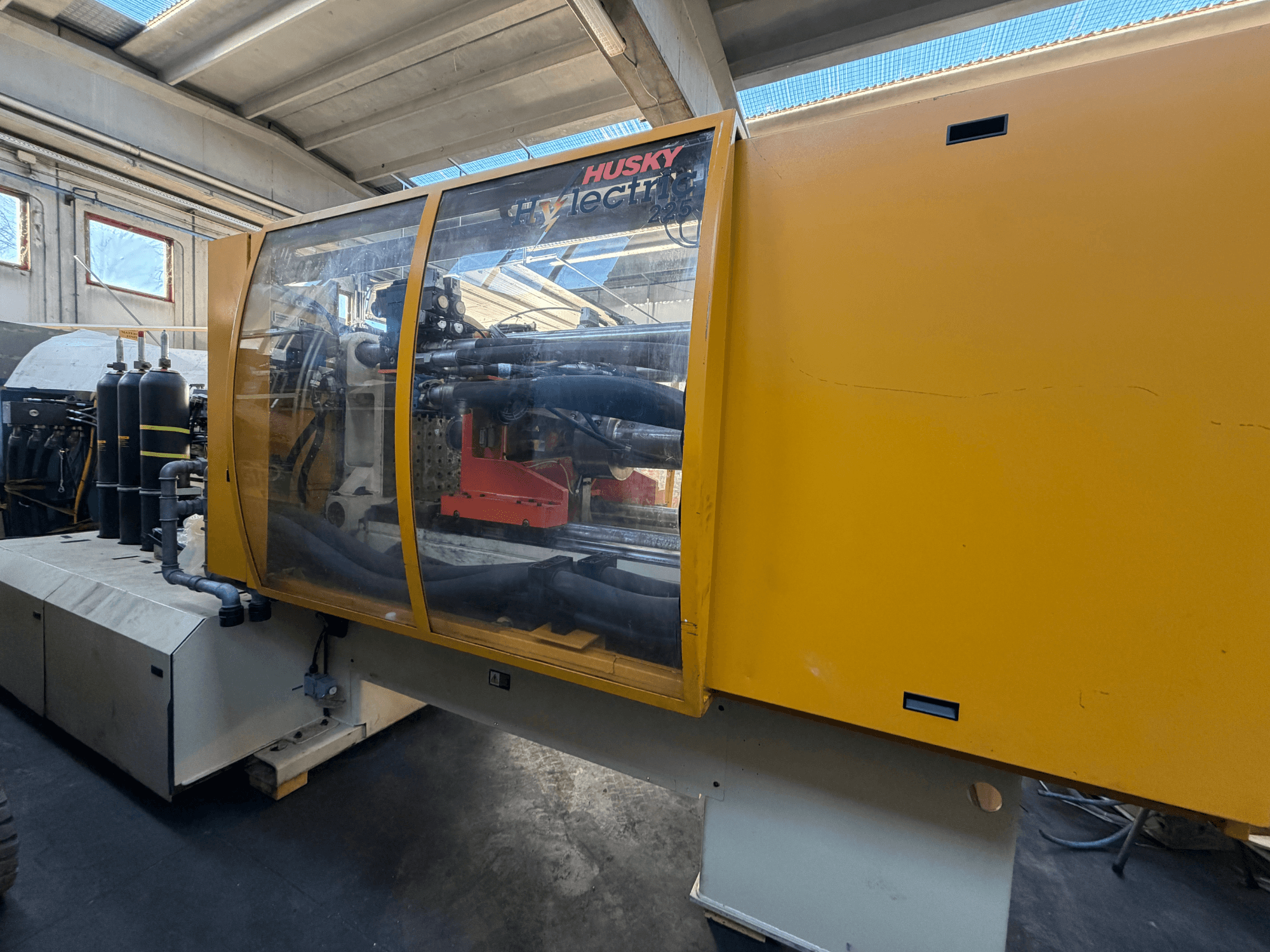 Husky HL225 RS65 electrical injection moulding machine, front view with yellow casing, visible control panel and hydraulic components.