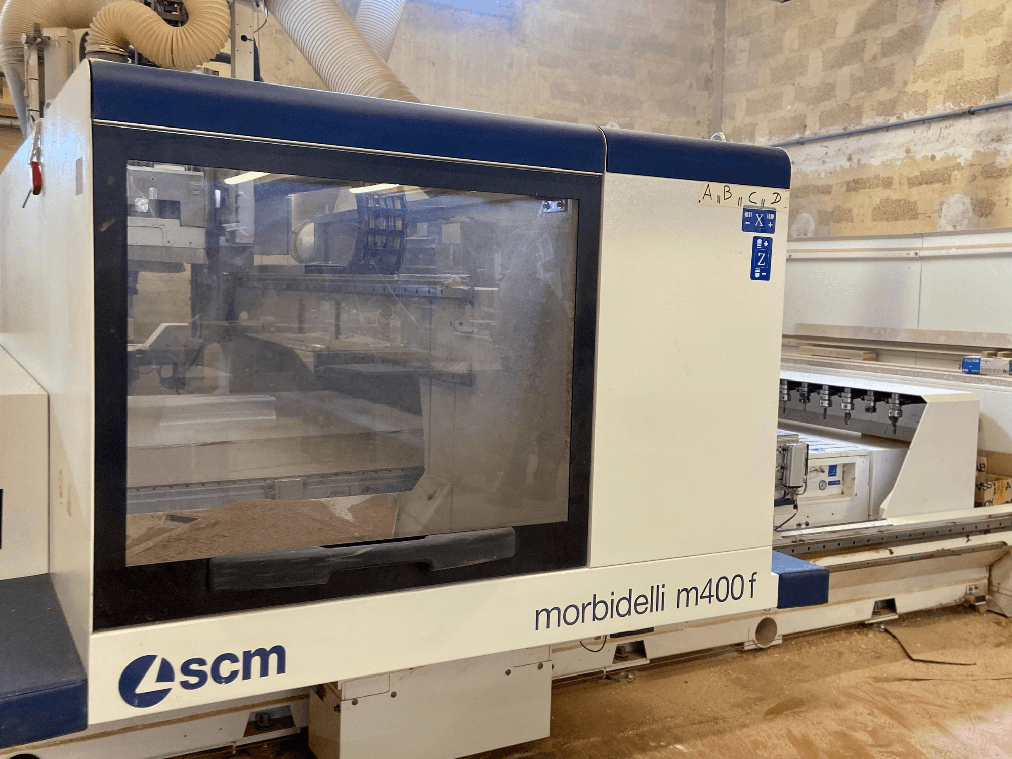 SCM Morbidelli M400F CNC machine, front view, featuring a control panel and visible sawdust on the floor.