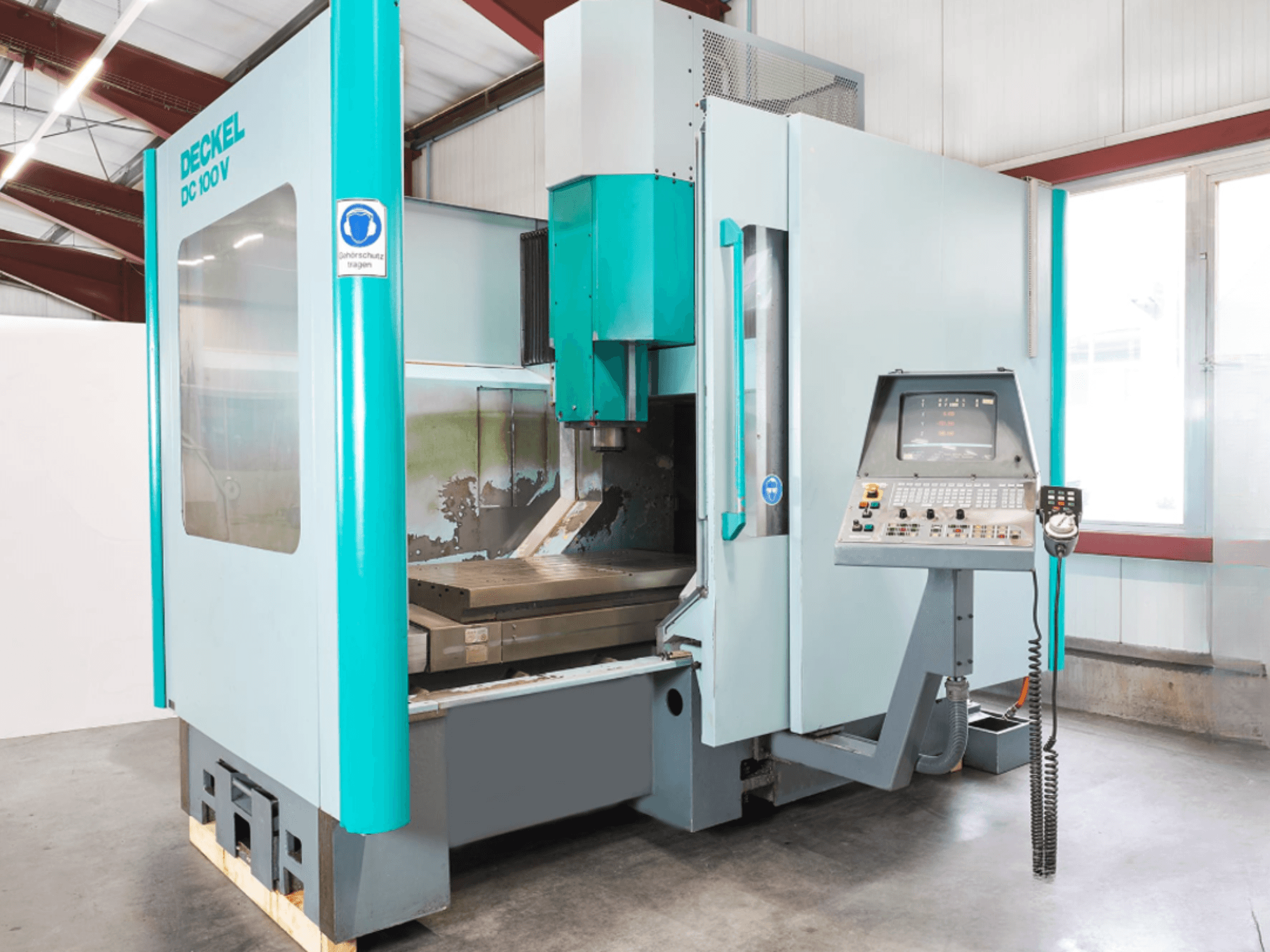 Deckel DC 100 V vertical machining center, front view, featuring digital control panel and cutting table.