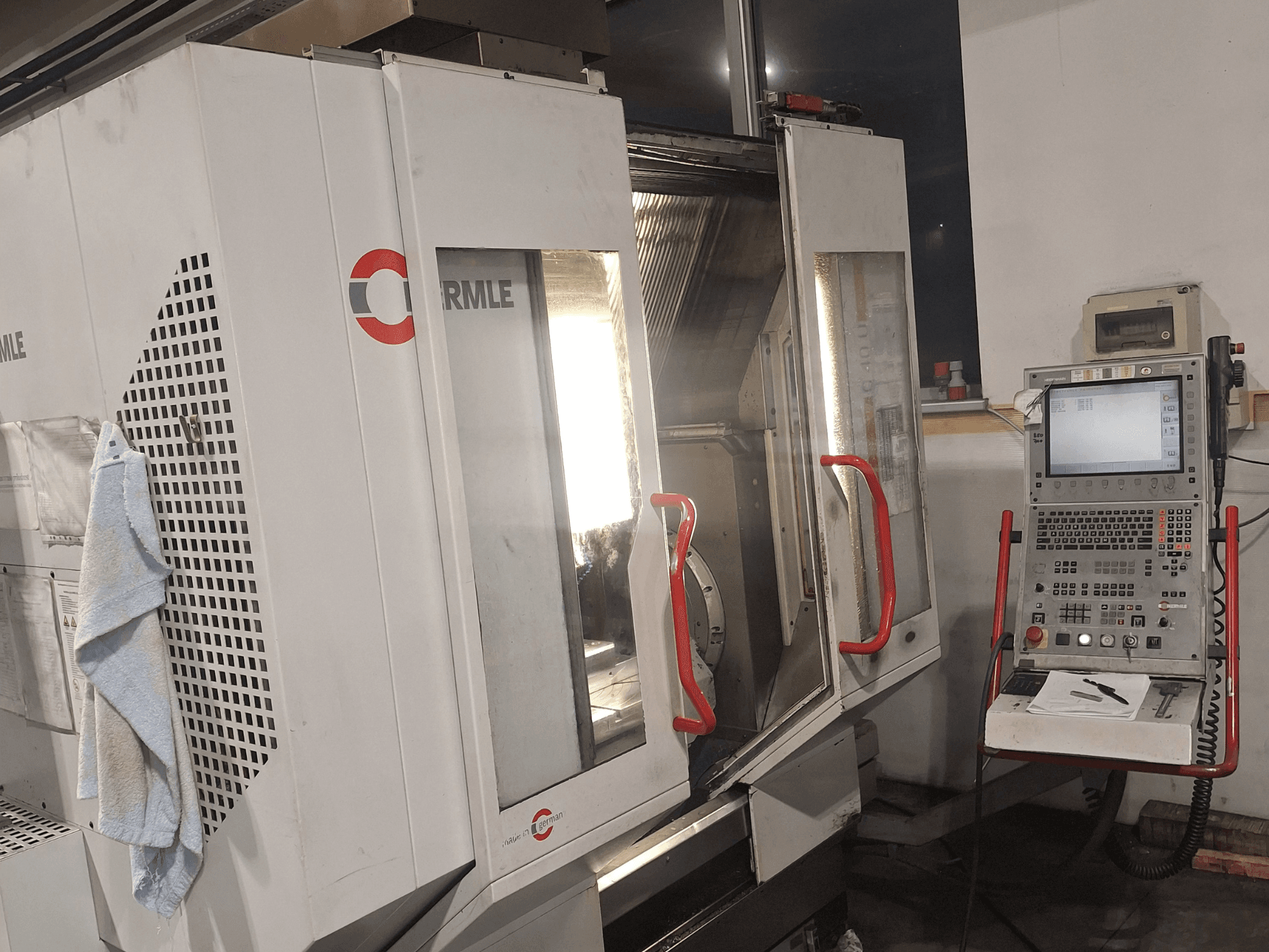 CNC machine from brand Cormile, front view showing doors partially open and control panel with screen and buttons.