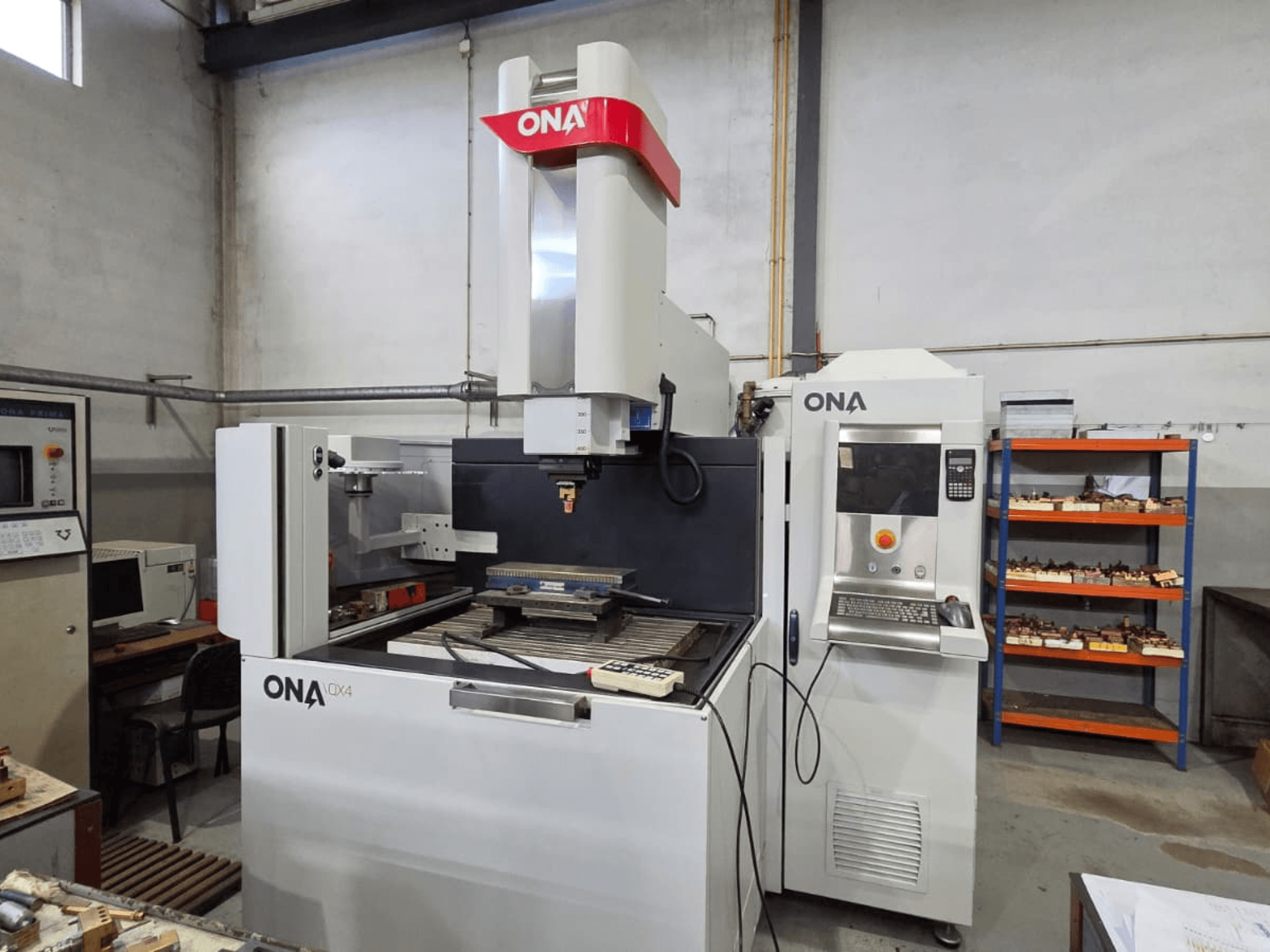 ONA QX4 die-sinking EDM machine in side view, featuring control panel and work table, located in a workshop setting.