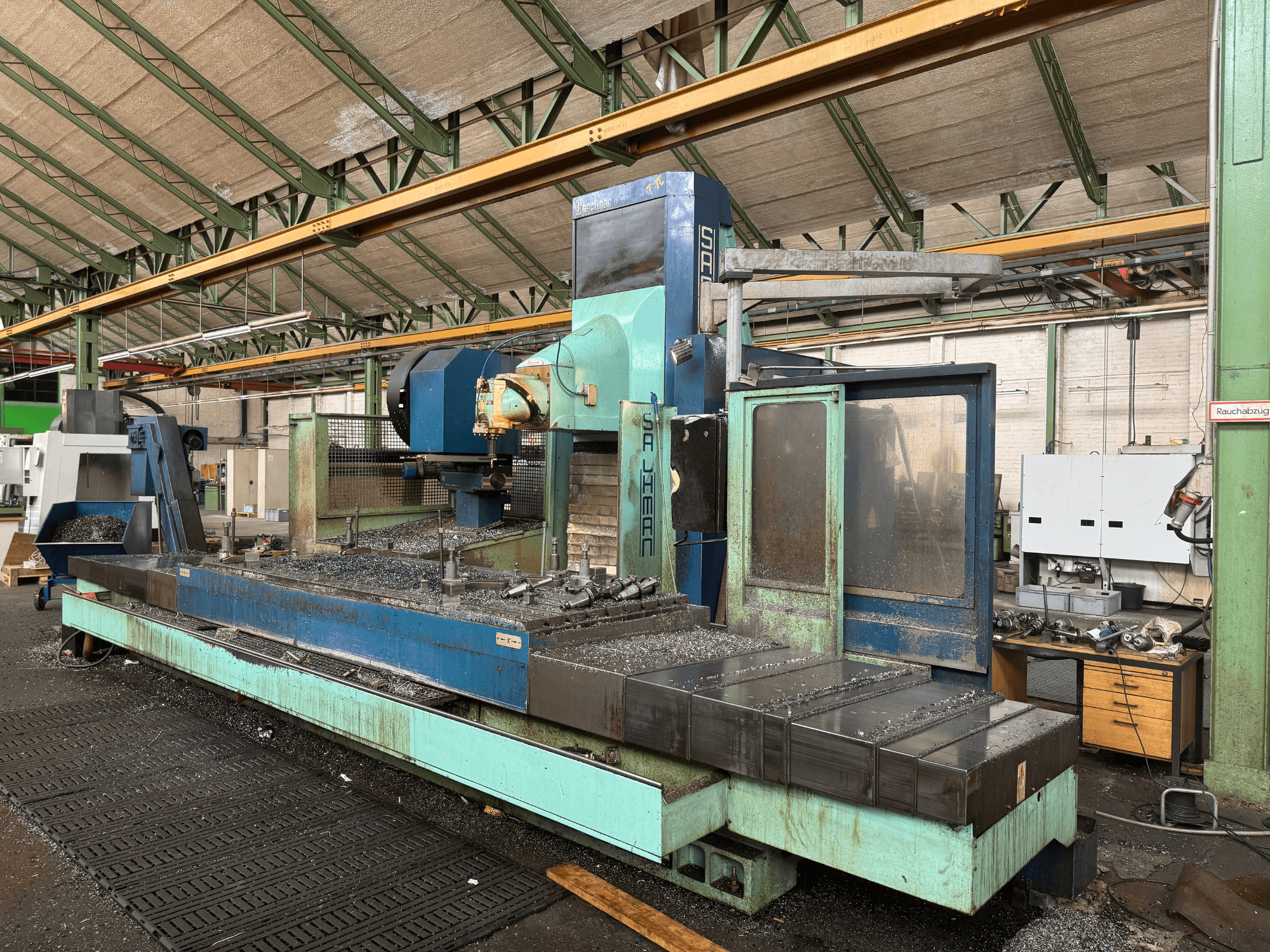 Salvador milling machine in factory setting, front view, with a blue and green color scheme, showing metal shavings on bed.