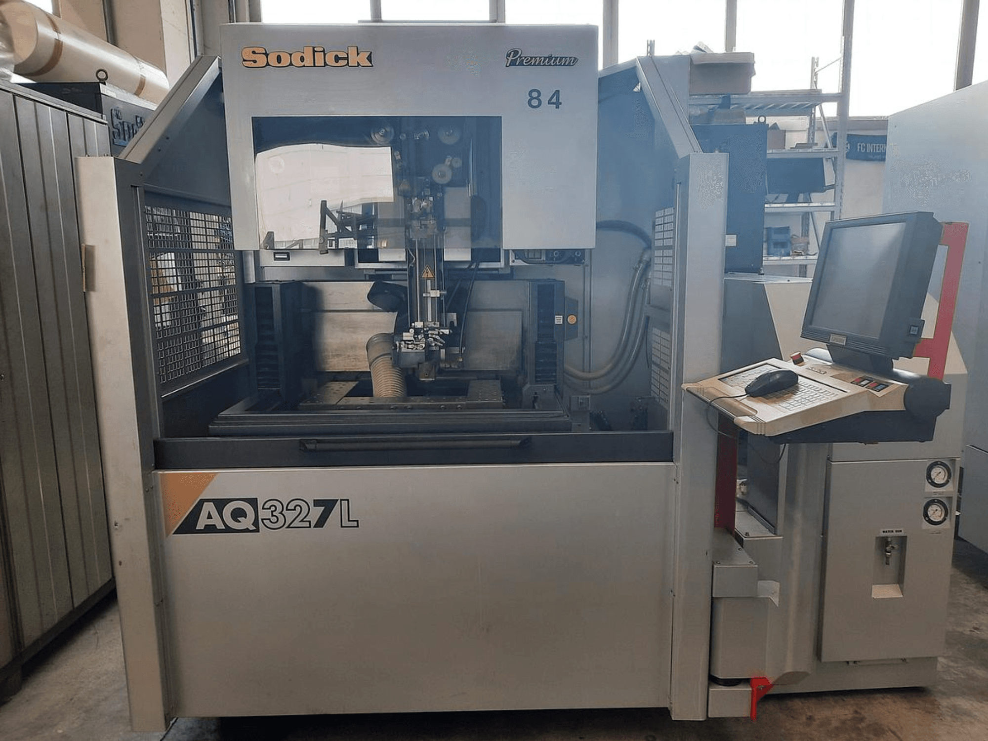 Sodick AQ327L machine in front view, featuring a control panel, user interface, and visible cutting area inside.