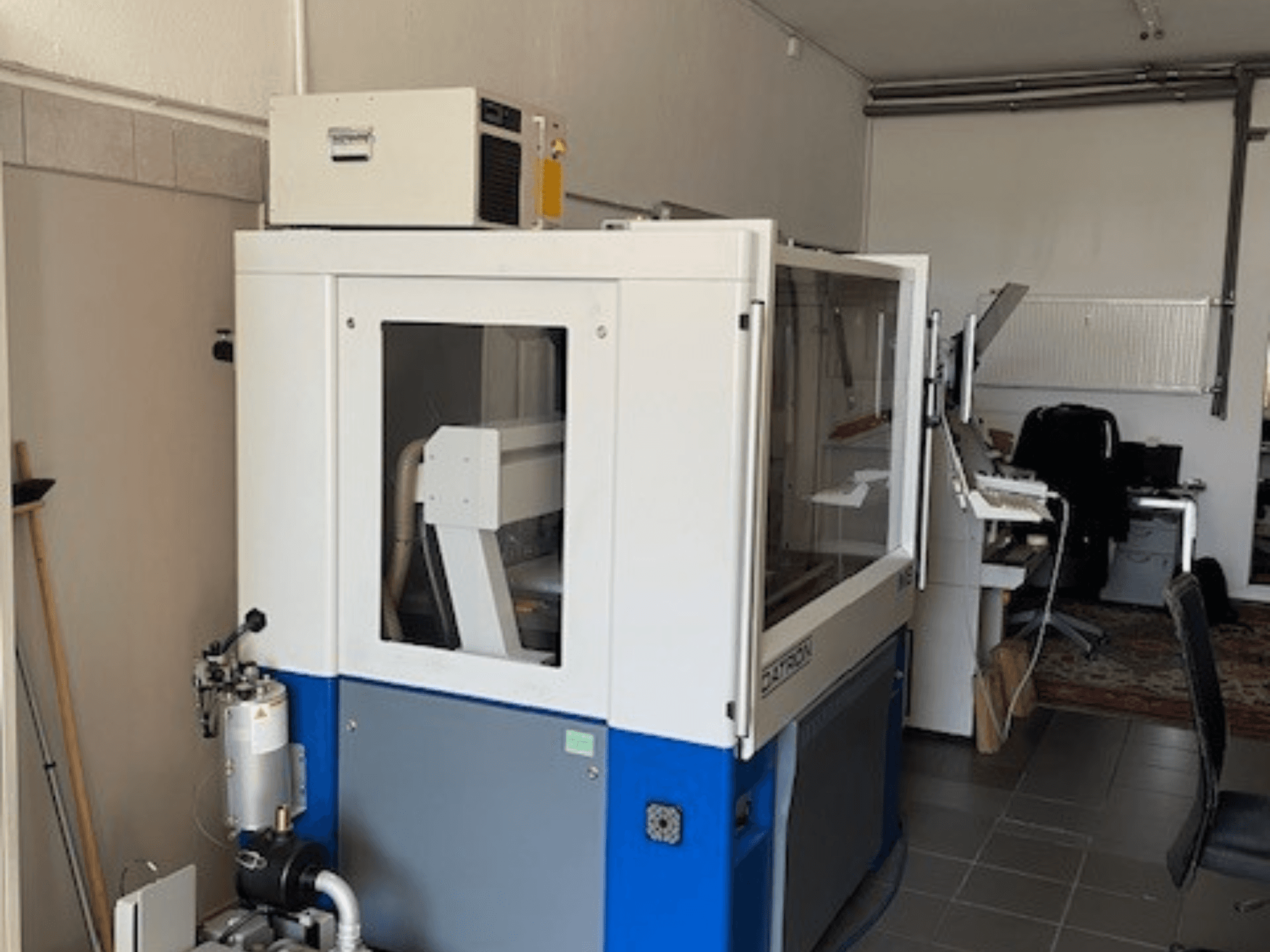 Blue and white industrial machine with transparent panels, front view, includes control access and visible ventilation unit.