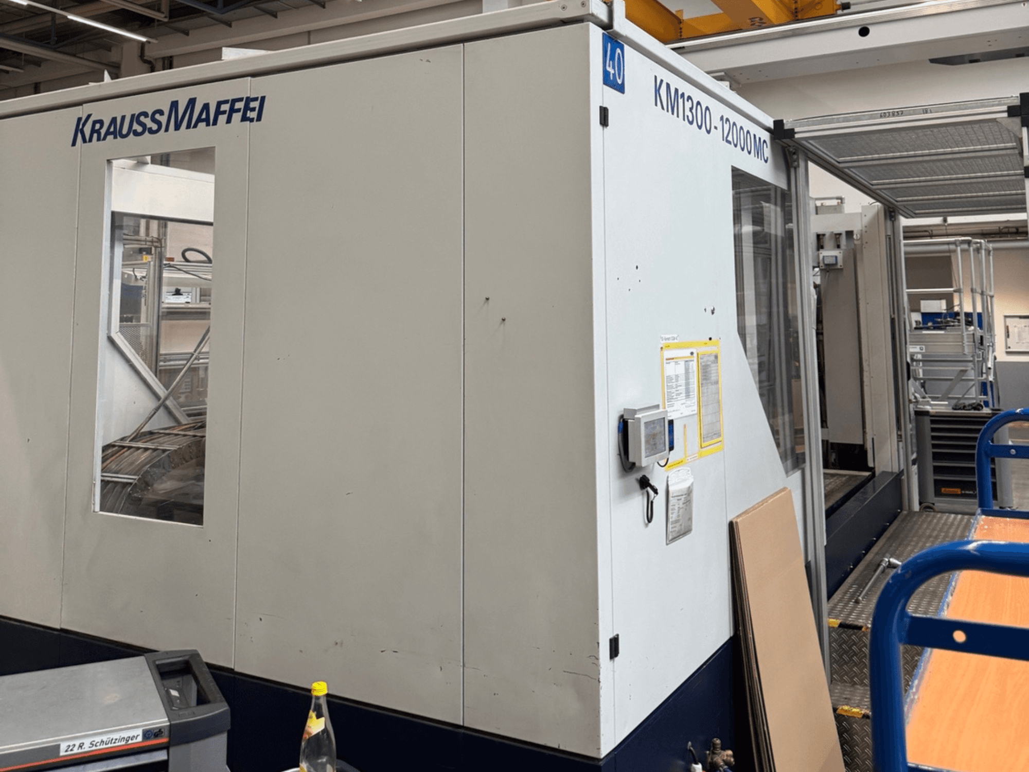 Krauss Maffei Hydraulic Injection Moulding Machine KM1300-12000 MC, side view, showcasing control panel and operational space.