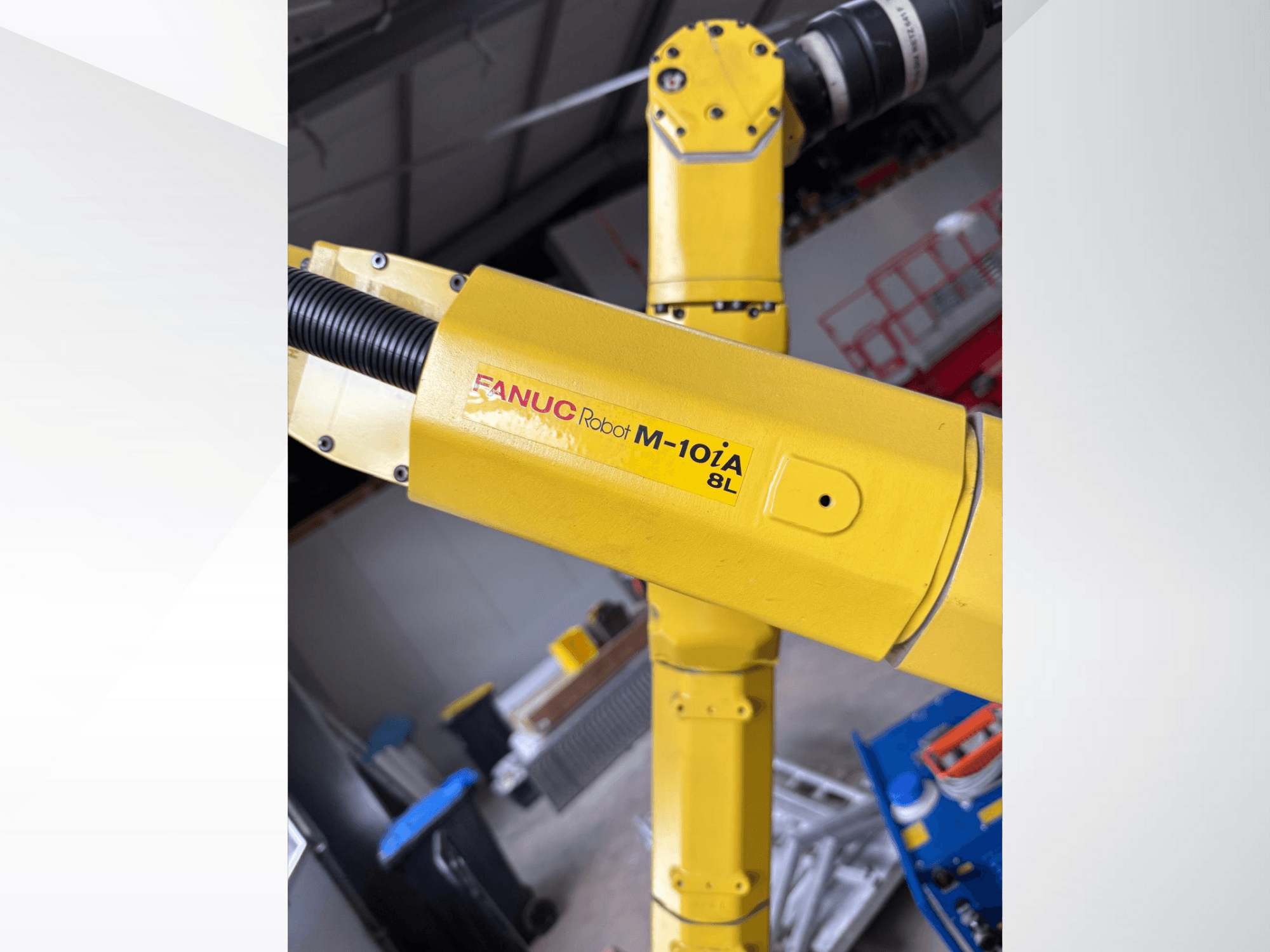 FANUC Robot M-10iA 8L in yellow, viewed from the side, showcasing arm joint and mechanical components in an industrial setting.