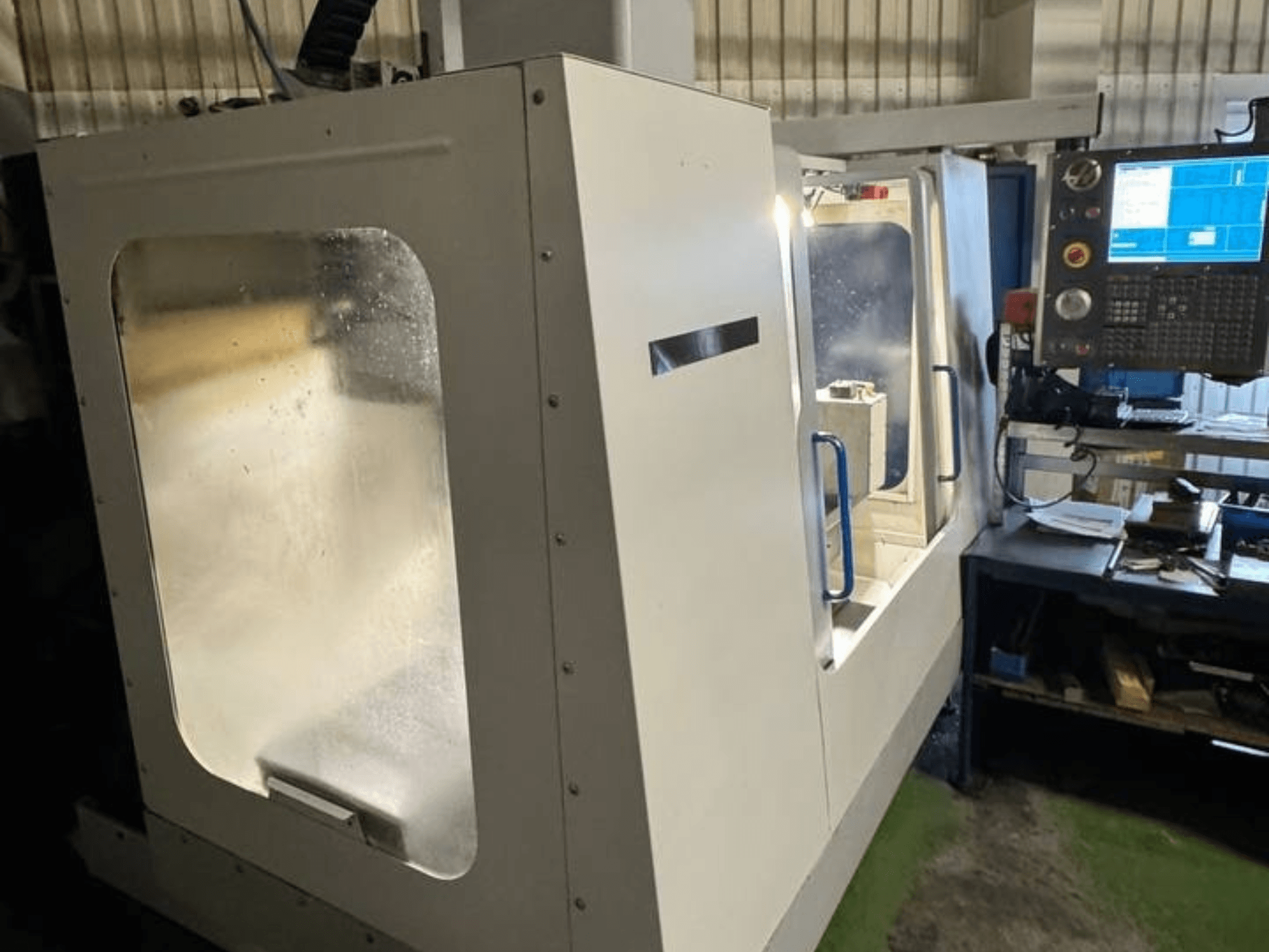 HAAS VCE 750 Vertical Machining Centre in side view, featuring a control panel and clear safety enclosure.