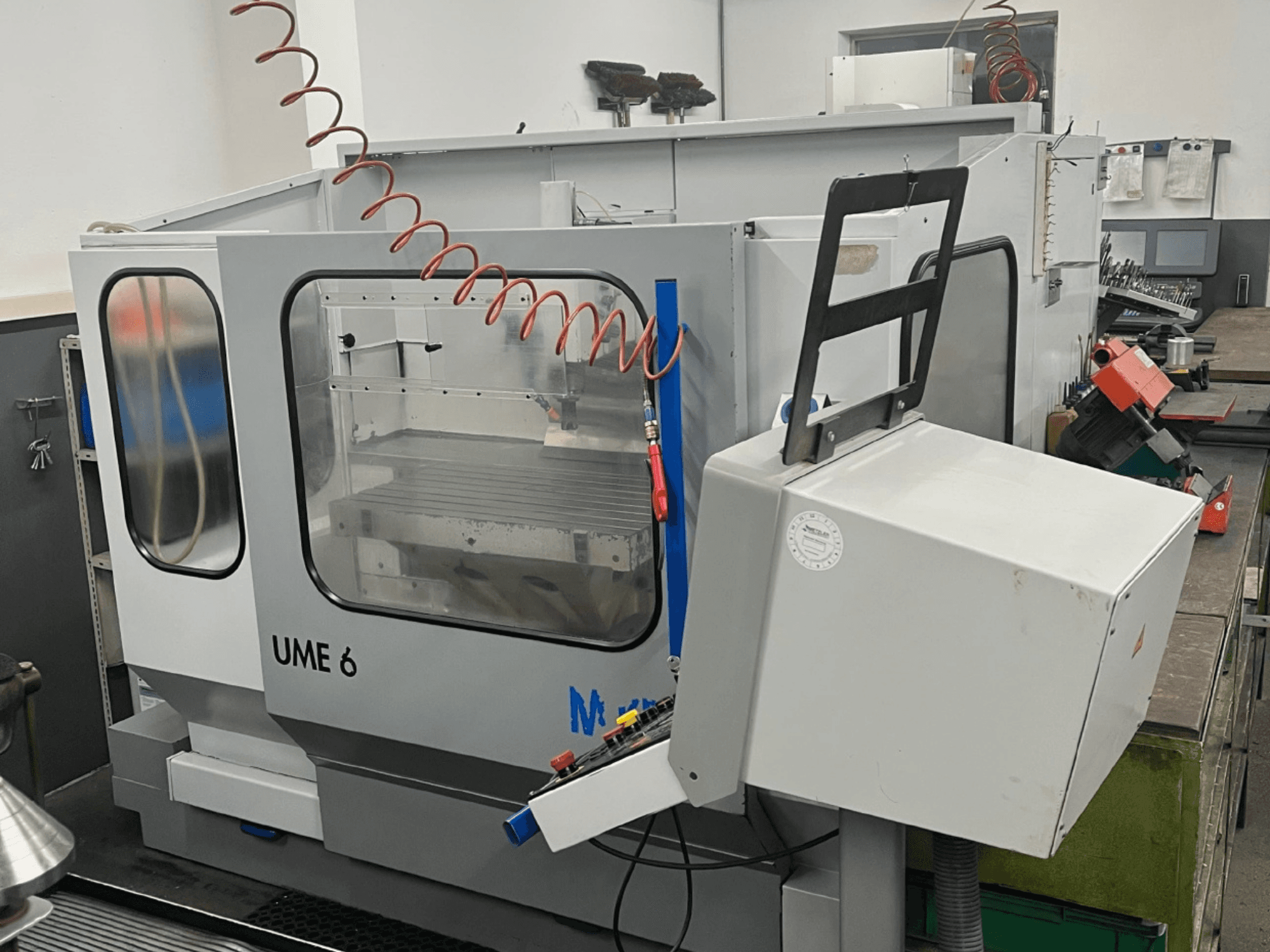 MIKRON UME600 Universal Machining Centre in a workshop, side view showing control panel and protective enclosure.