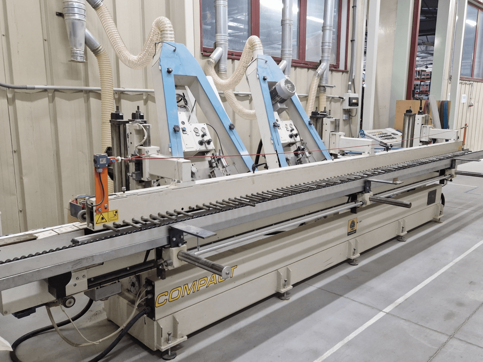 Belt sander TECNOLEGNO COMPACT 52 in a workshop, showing control panel and sanding belt mechanism from a side view.