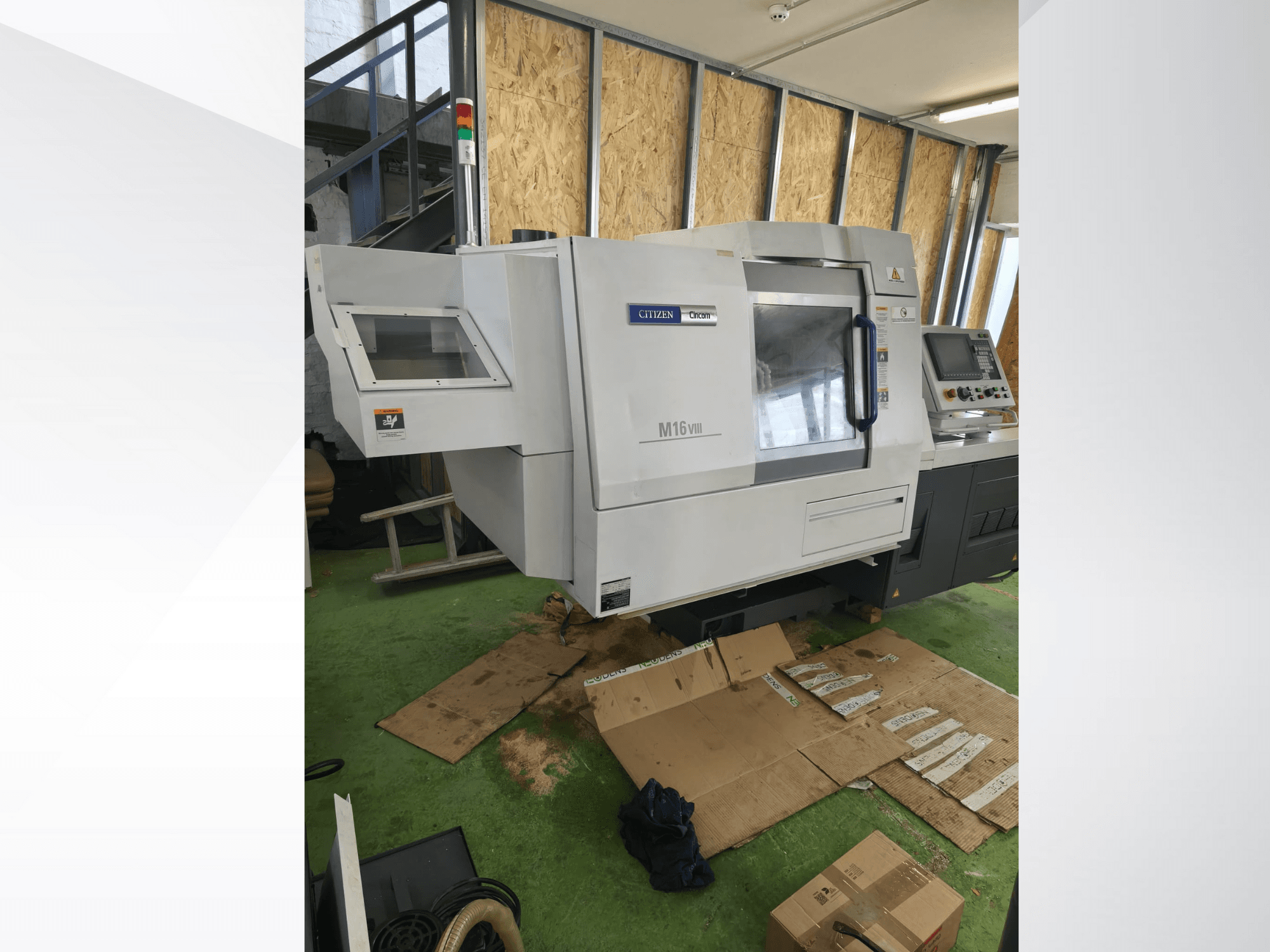 Citizen M16VIII CNC lathe in front view, features control panel and safety alert lights, placed on green flooring.