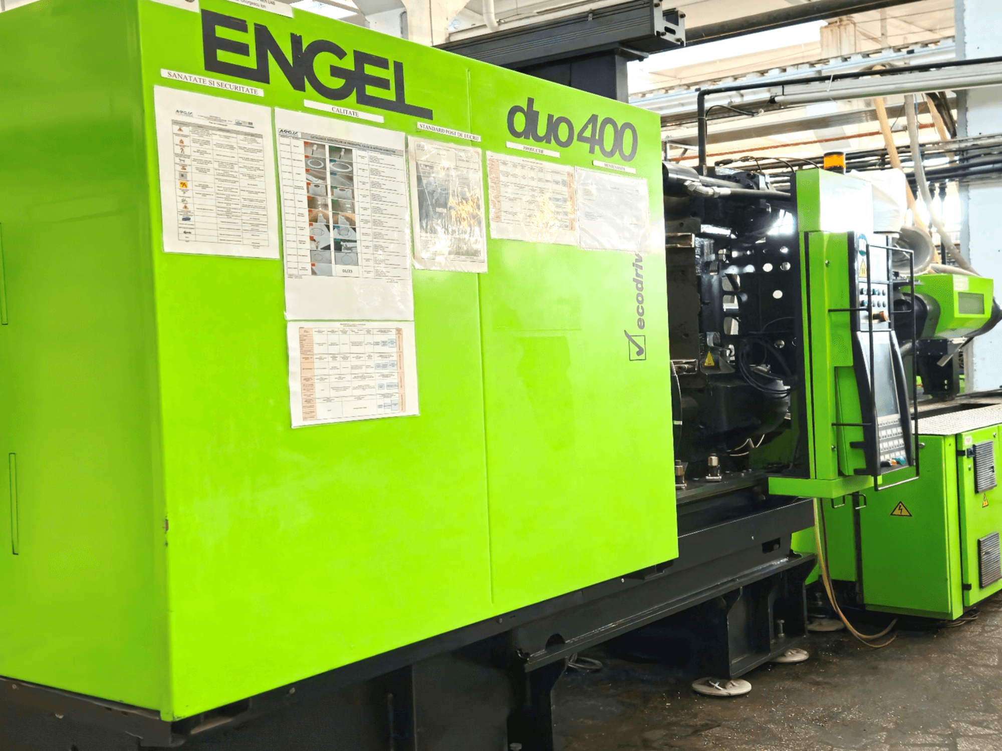 Green ENGEL duo 400 injection molding machine, front view, showcasing control panel and safety documentation on exterior.