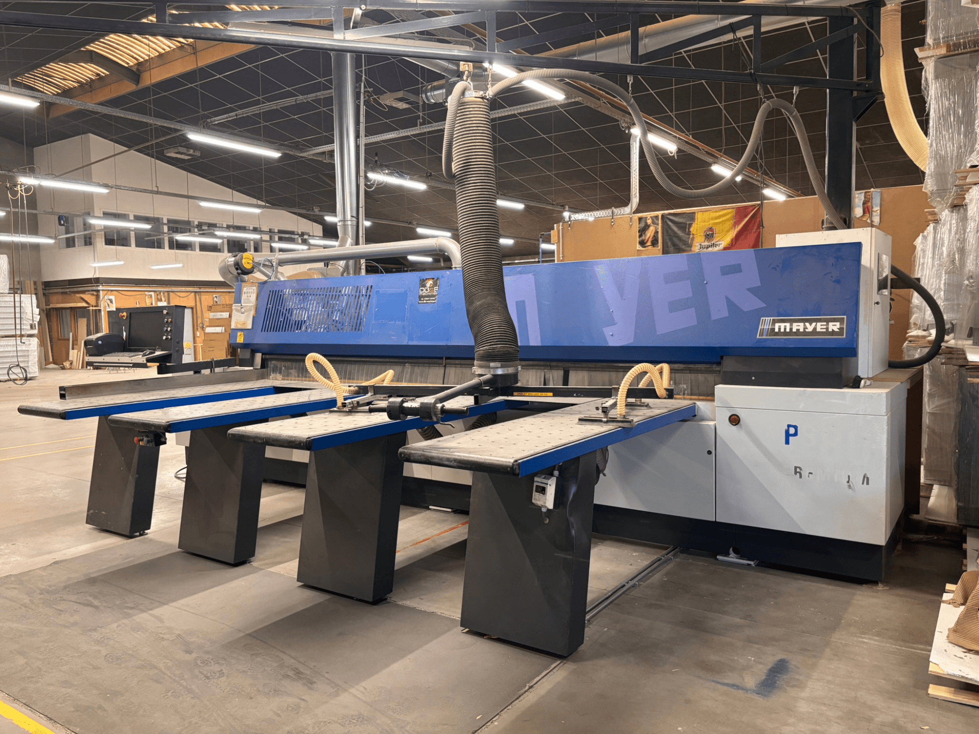 Mayer CNC machine with blue panels, front view; features multiple work tables and a dust extraction system for woodworking.