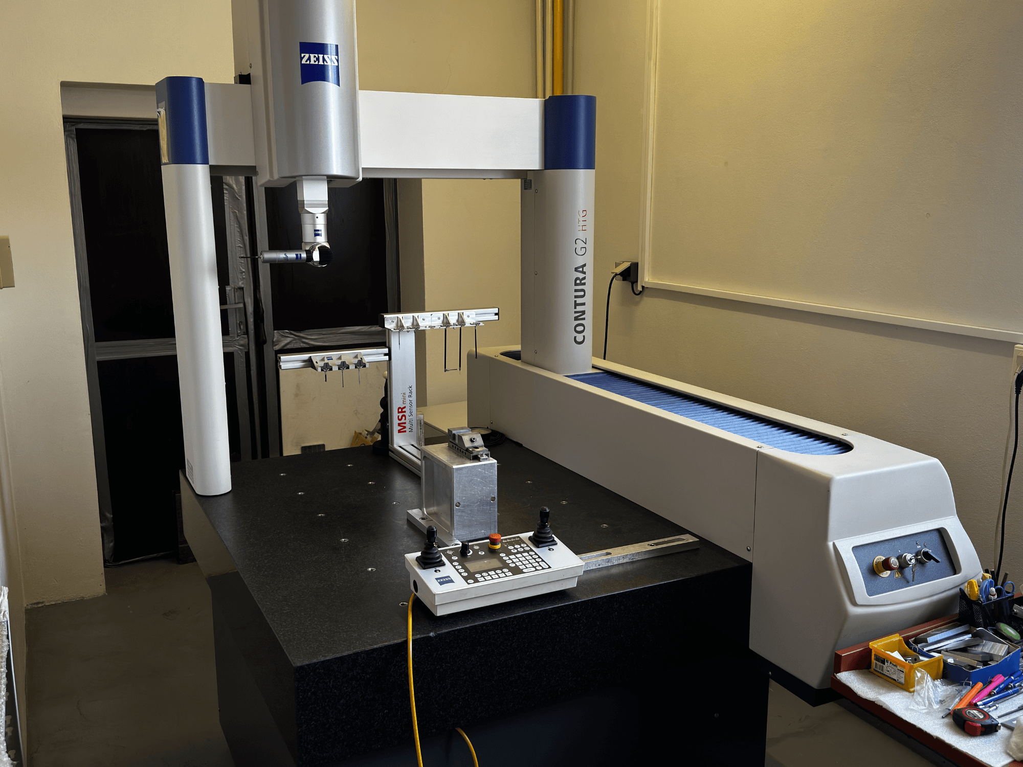 ZEISS Contura G2 CMM in a lab setting, front view showcasing measurement arm, control panel, and adjacent workspace.
