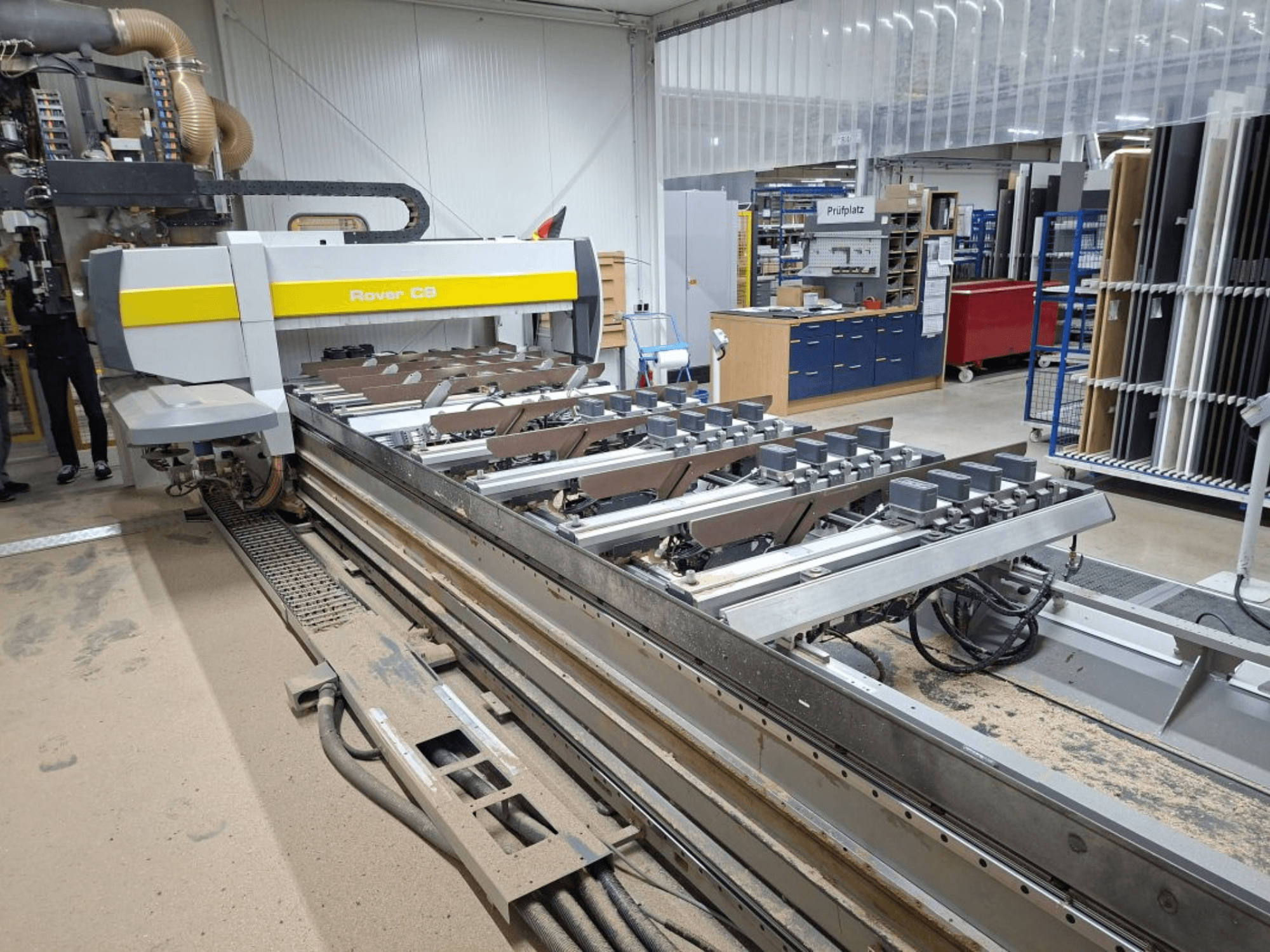 Rover C9 CNC machine in a workshop, front view, with a cutting bed and multiple clamps visible, surrounded by equipment.
