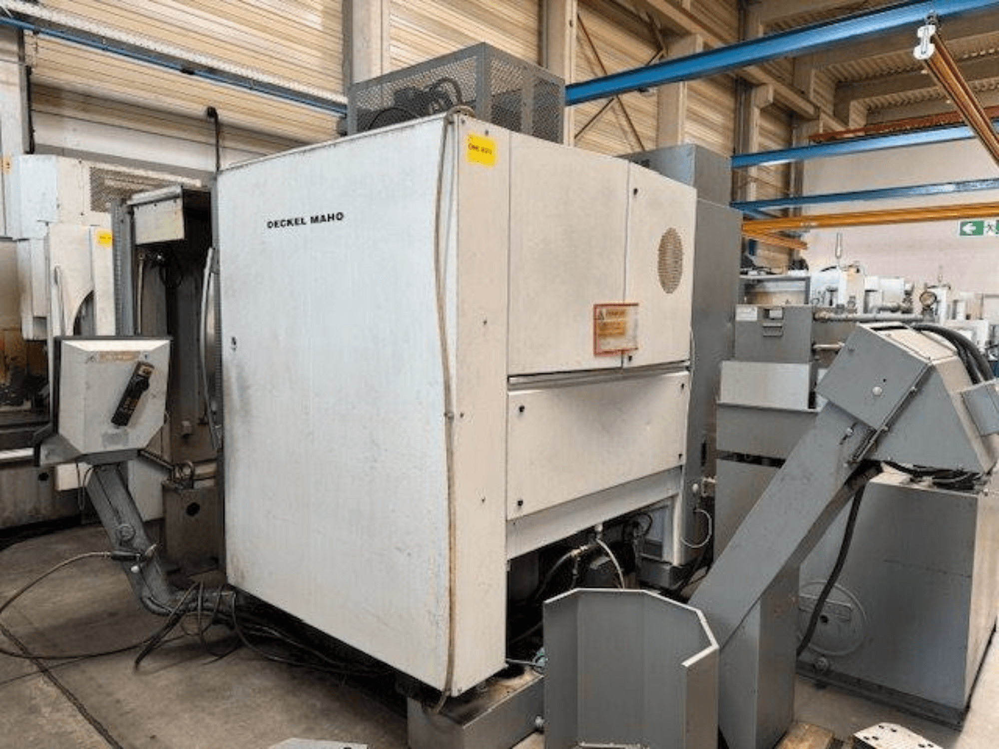 DECKEL MAHO DMC 100 V vertical machining centre, side view with control panel and various attachments visible.